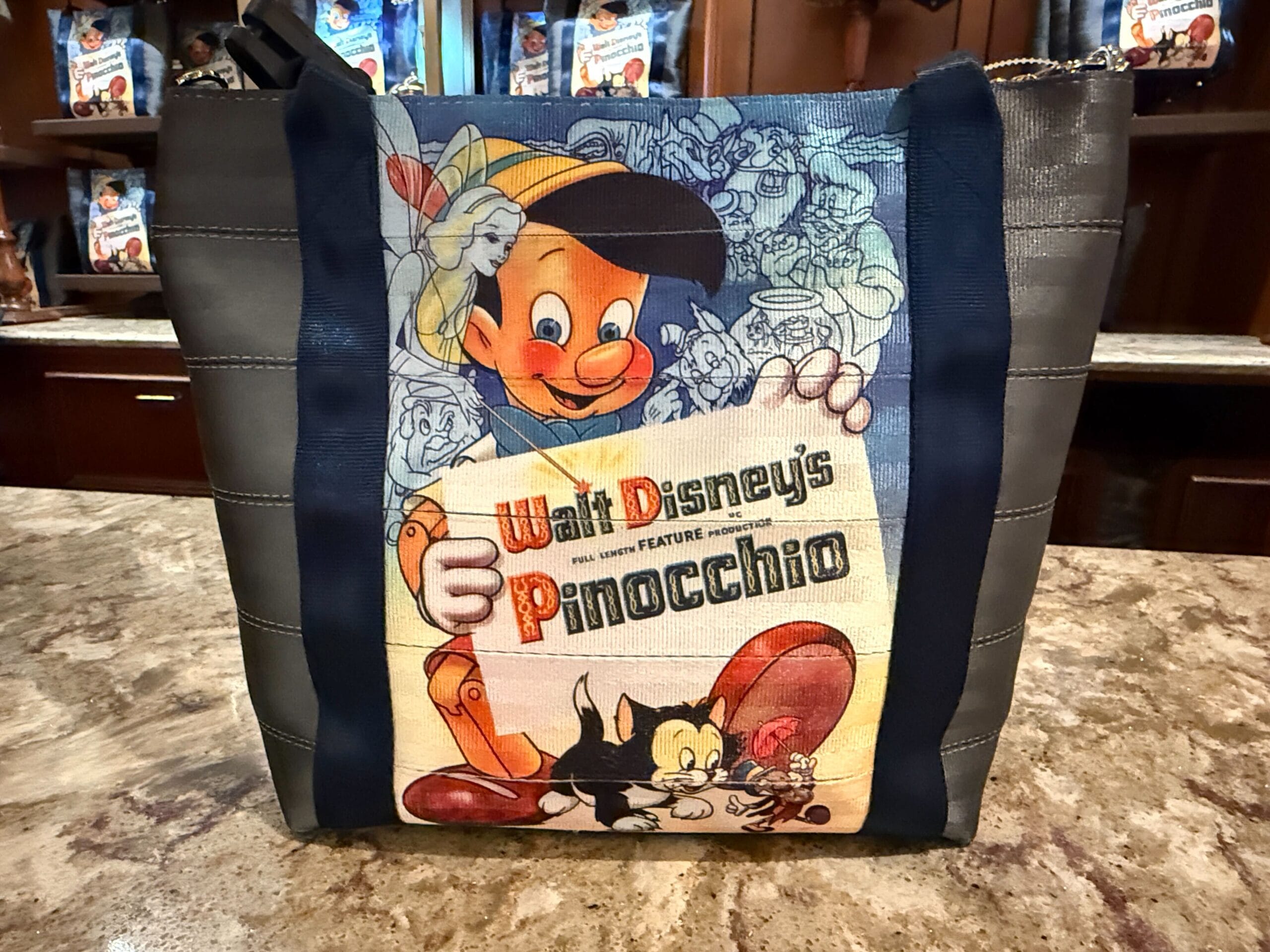 A tote bag featuring vintage Walt Disney’s Pinocchio artwork sits on a marble countertop in a store.
