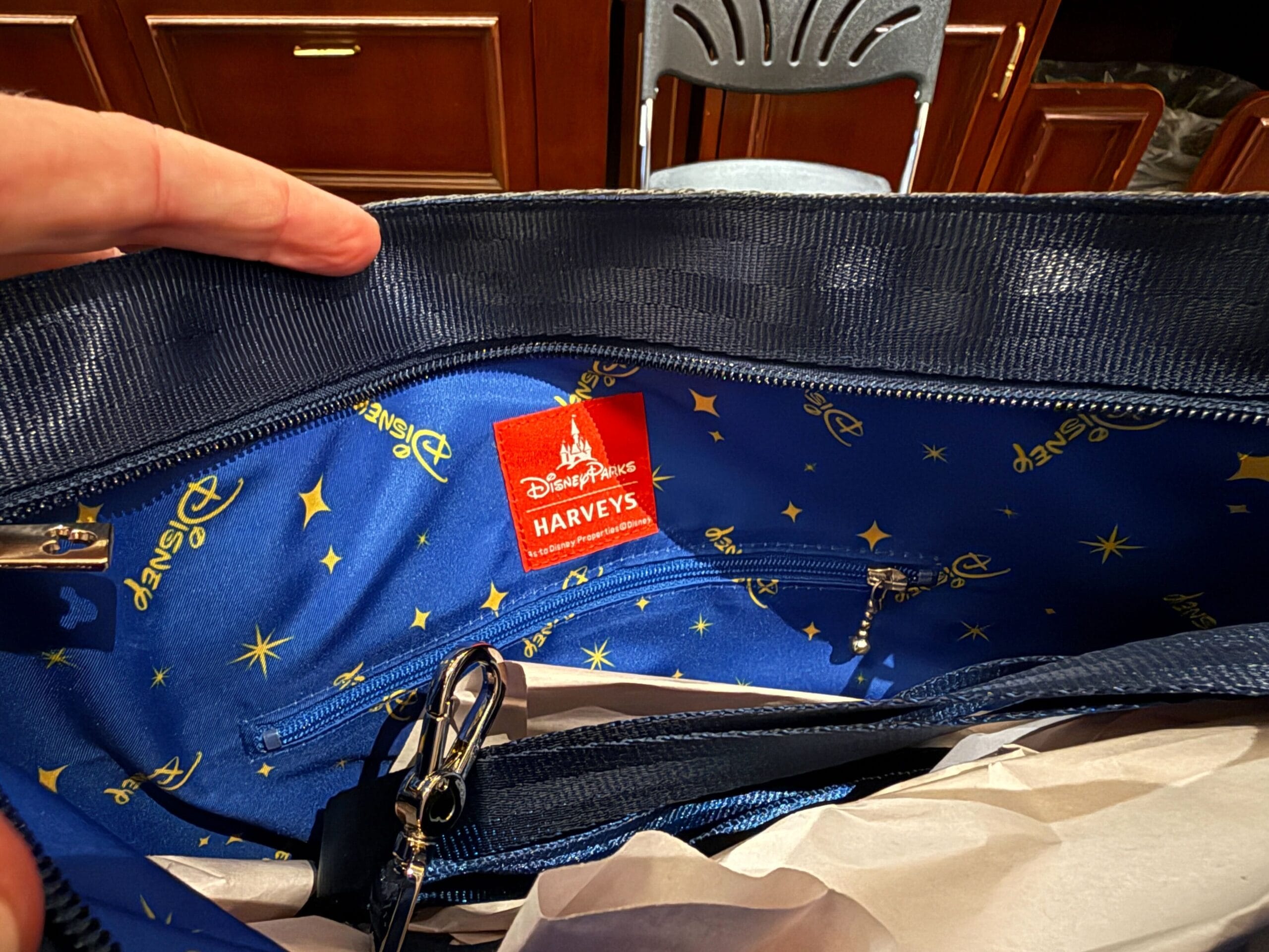 The inside of a purse with a blue, star-patterned Disney Parks x Harveys lining and a red logo tag.