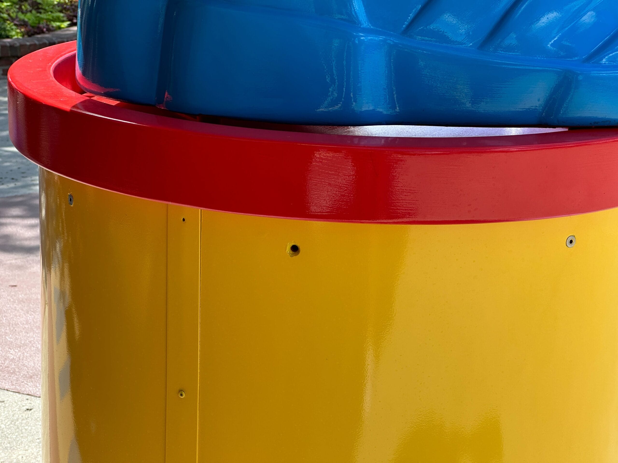 A close-up of a yellow structure with a red rim and a large blue object on top.