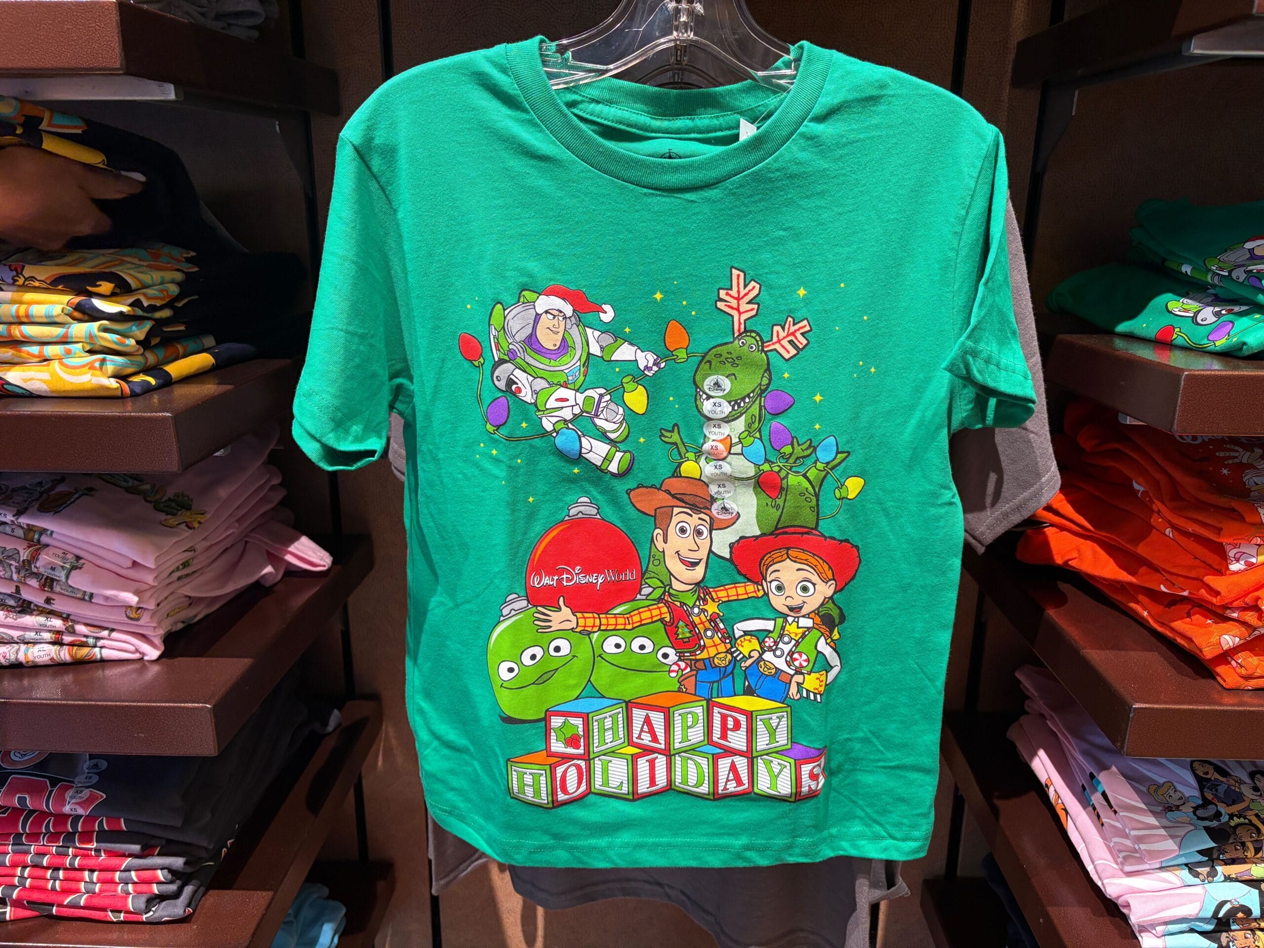 Green T-shirt with Toy Story characters and "Happy Holidays" blocks, decorated with Christmas lights and festive designs.