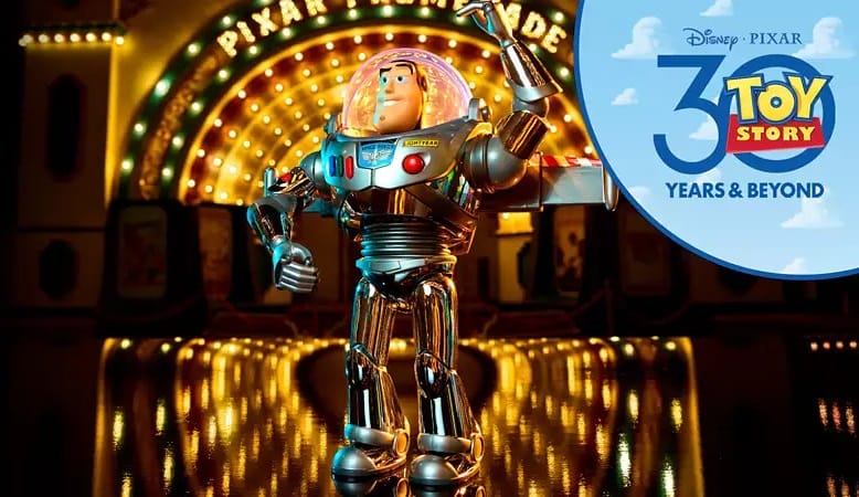 Buzz Lightyear toy stands before bright park lights; Toy Story 30th Anniversary logo in corner, reminiscent of Disney park shops.