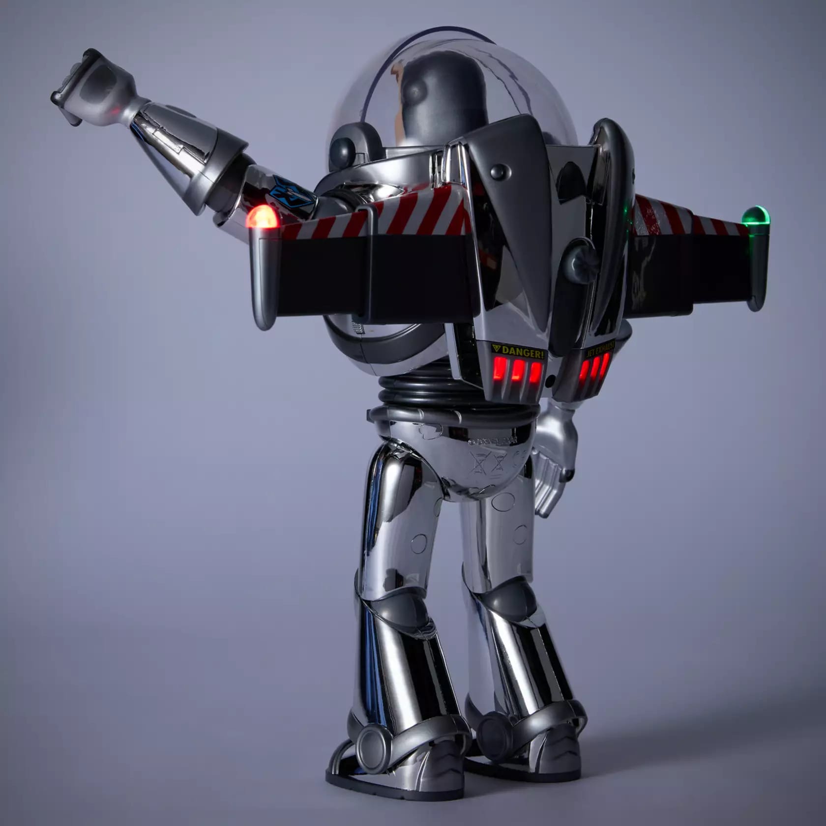 Limited edition chrome Buzz Lightyear action figure seen from the back with wings extended and left arm doing a karate chop.