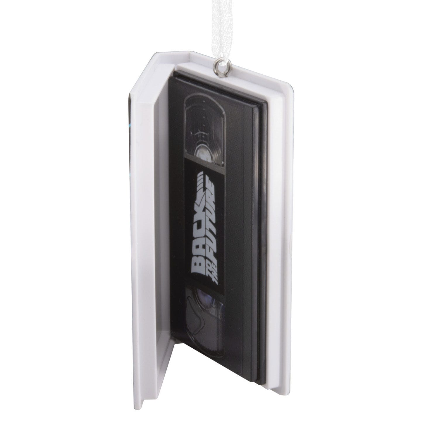 Hanging ornament shaped like a VHS tape in a white clamshell, reminiscent of vintage Disney movie releases at park gift shops.