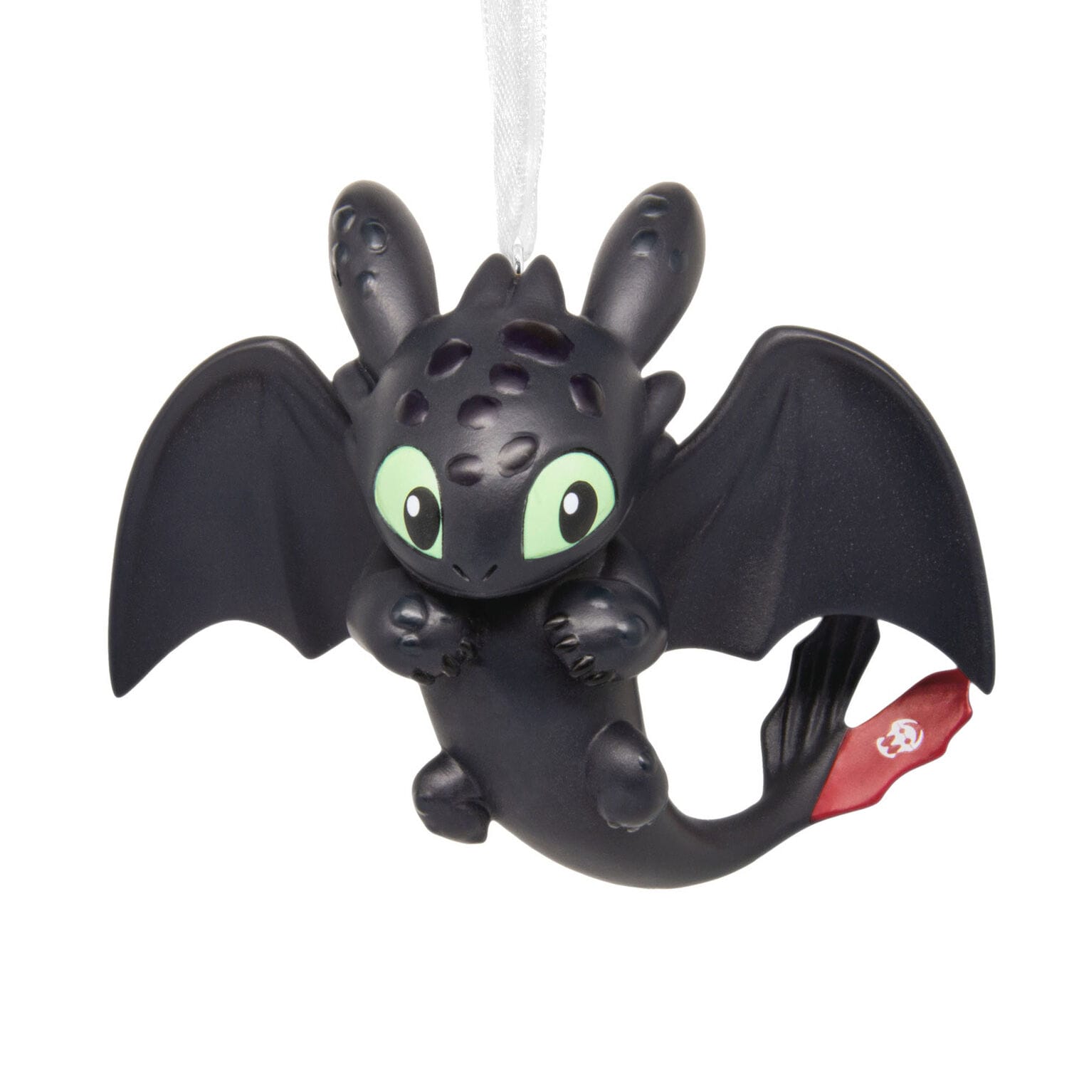 A cute black dragon Hallmark ornament with green eyes, wide wings, and a red tail fin hangs by a white ribbon