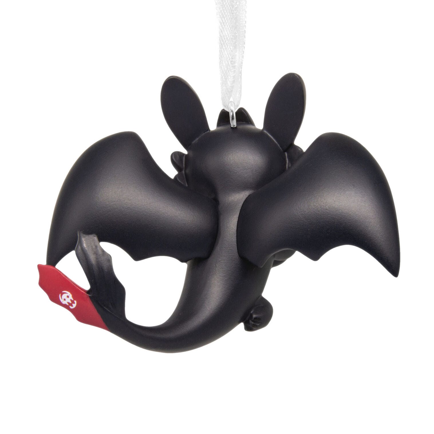 A black dragon ornament with large wings and a red tail fin, reminiscent of Universal Studios, hangs on a white ribbon