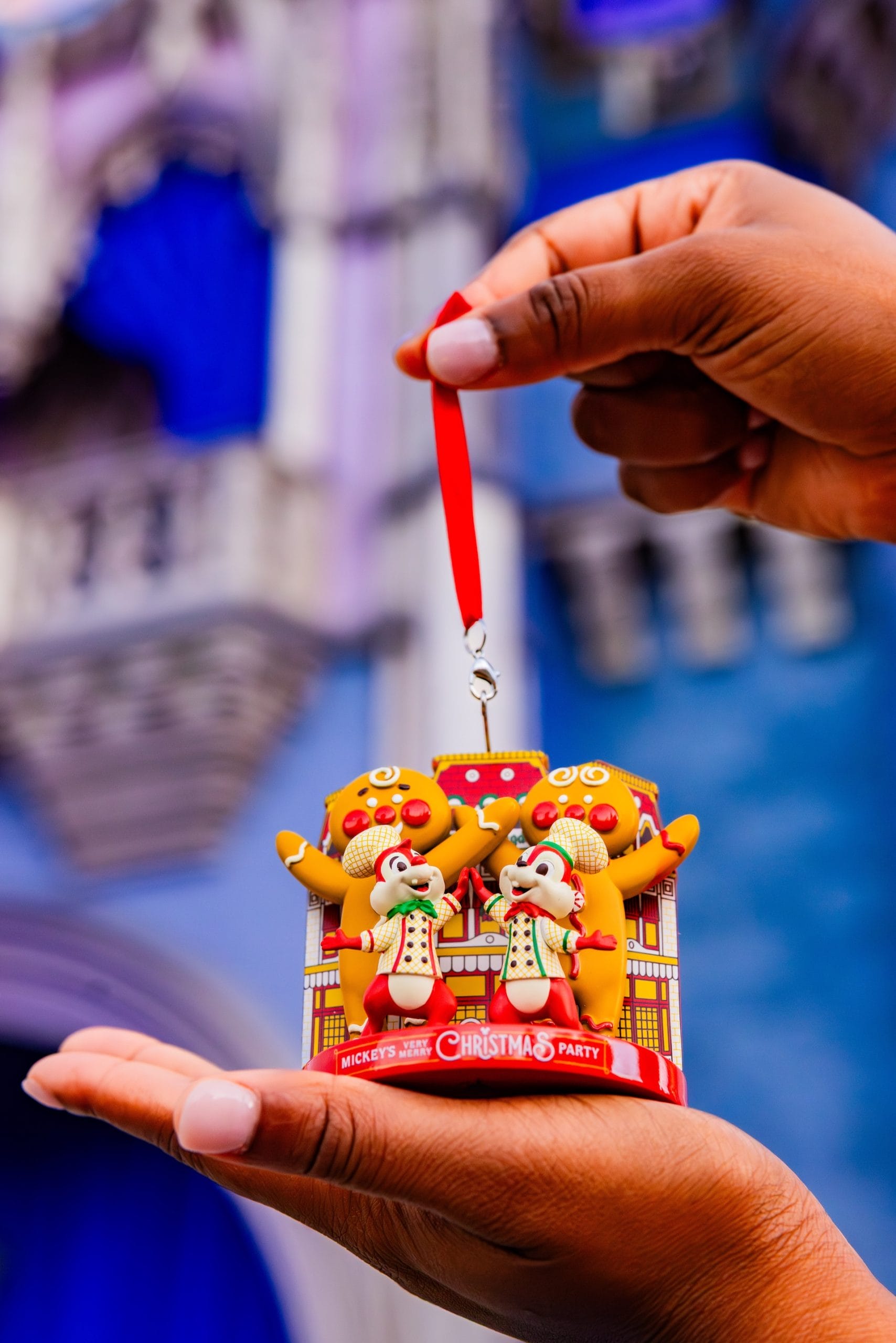 A person displays 2025 Mickey’s Very Merry Christmas Party items before a castle resembling Cinderella Castle at Walt Disney World.