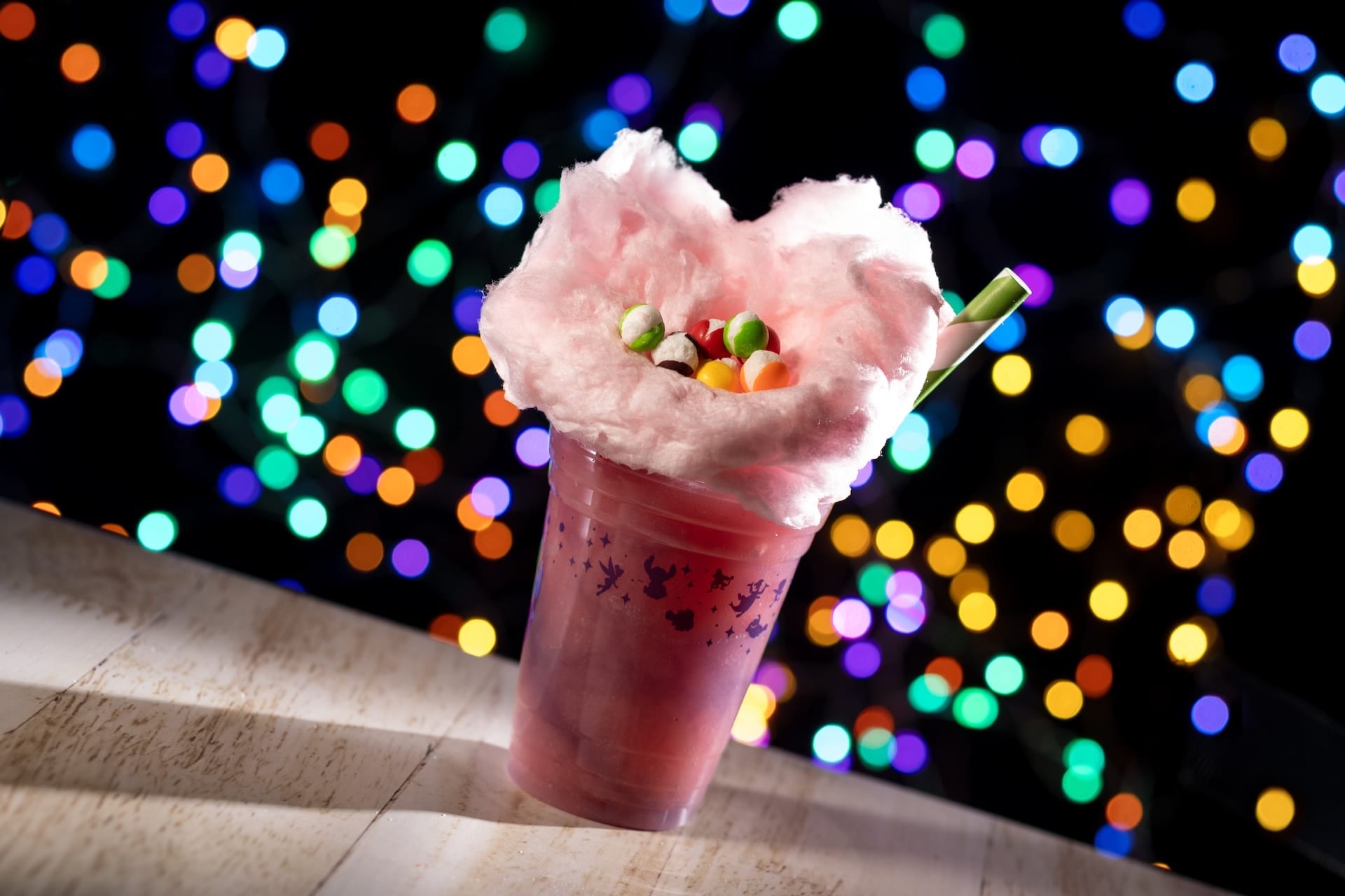 A pink Disney-inspired beverage topped with cotton candy and colorful candies, capturing the whimsy of Jollywood Nights treats.