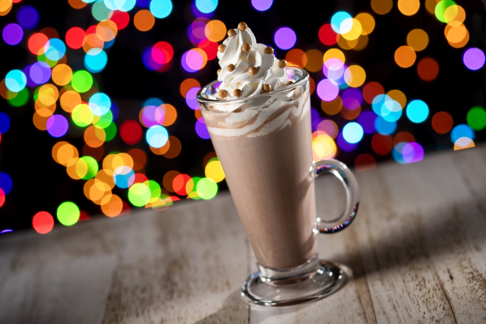 Glass mug of hot chocolate crowned with whipped cream, a cozy Disney Jollywood Nights treat—just steps from Hollywood Studios, no castle in sight.