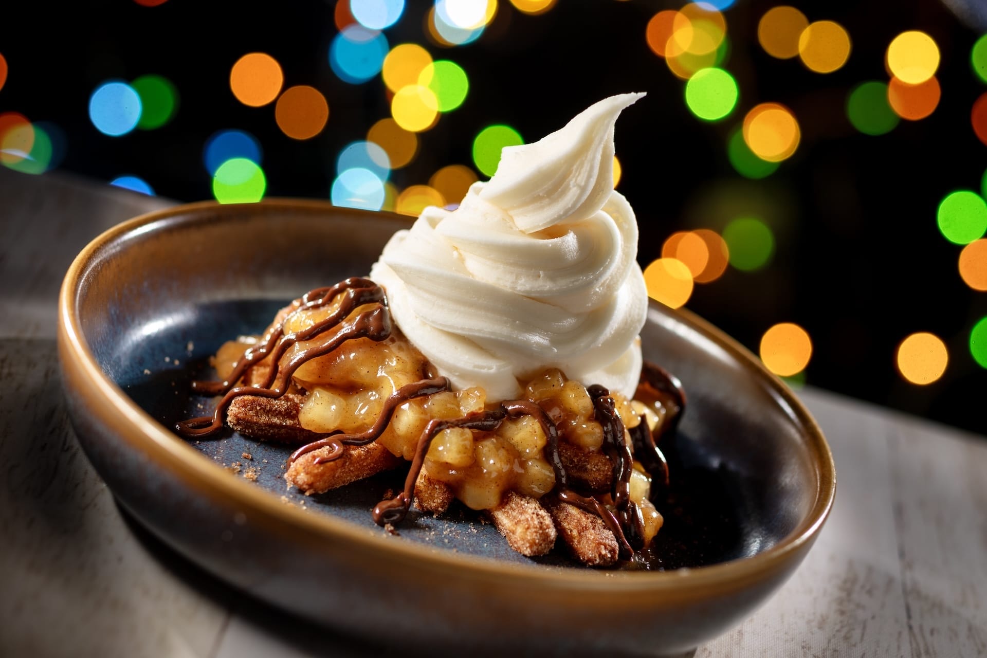 Vanilla soft serve swirled atop caramelized pecans and apples, chocolate drizzle, served at Disney Jollywood Nights 2025.