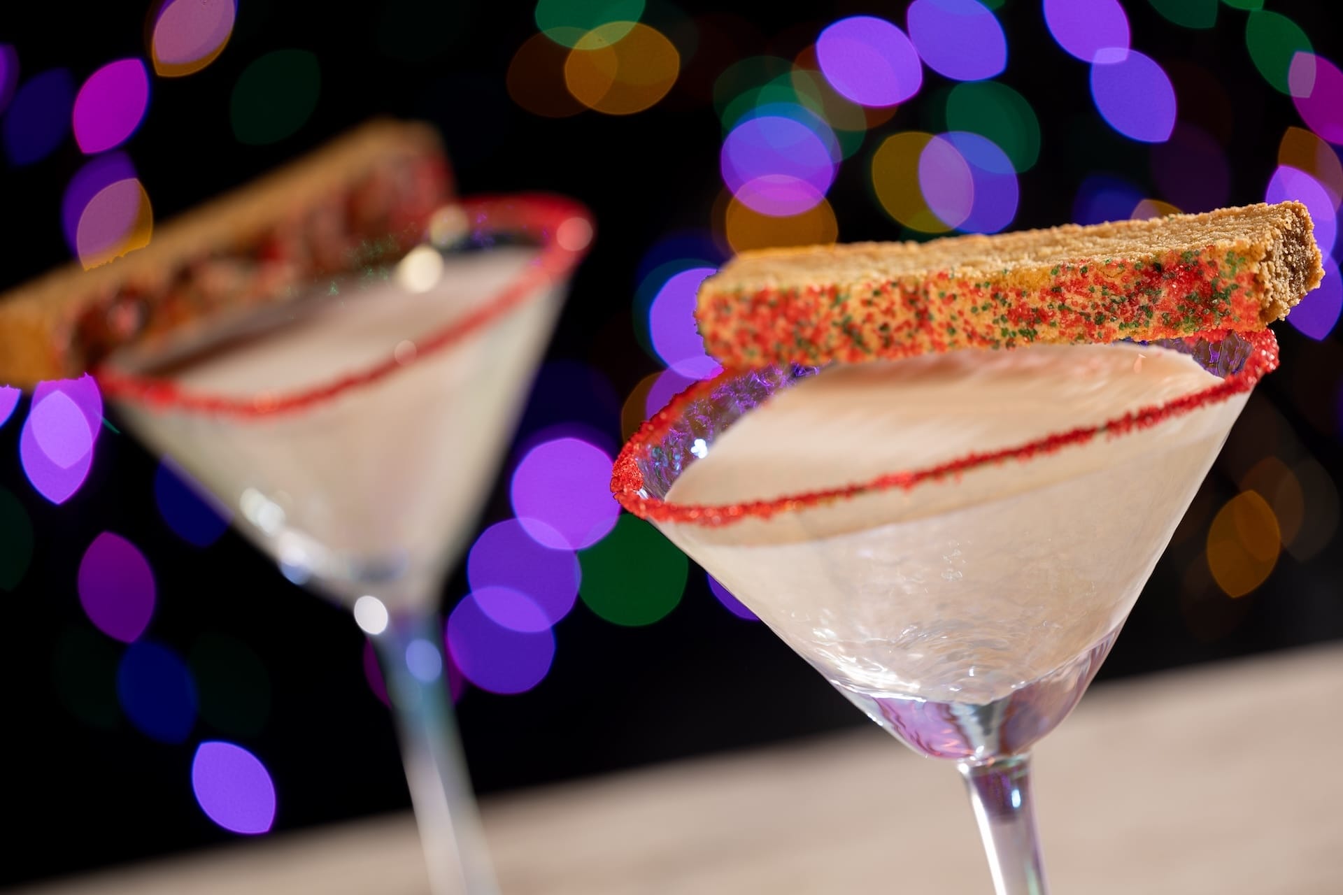 Two martini glasses with red sugar rims and biscotti, highlighting new 2025 Disney Jollywood Nights treats at a Disney park.