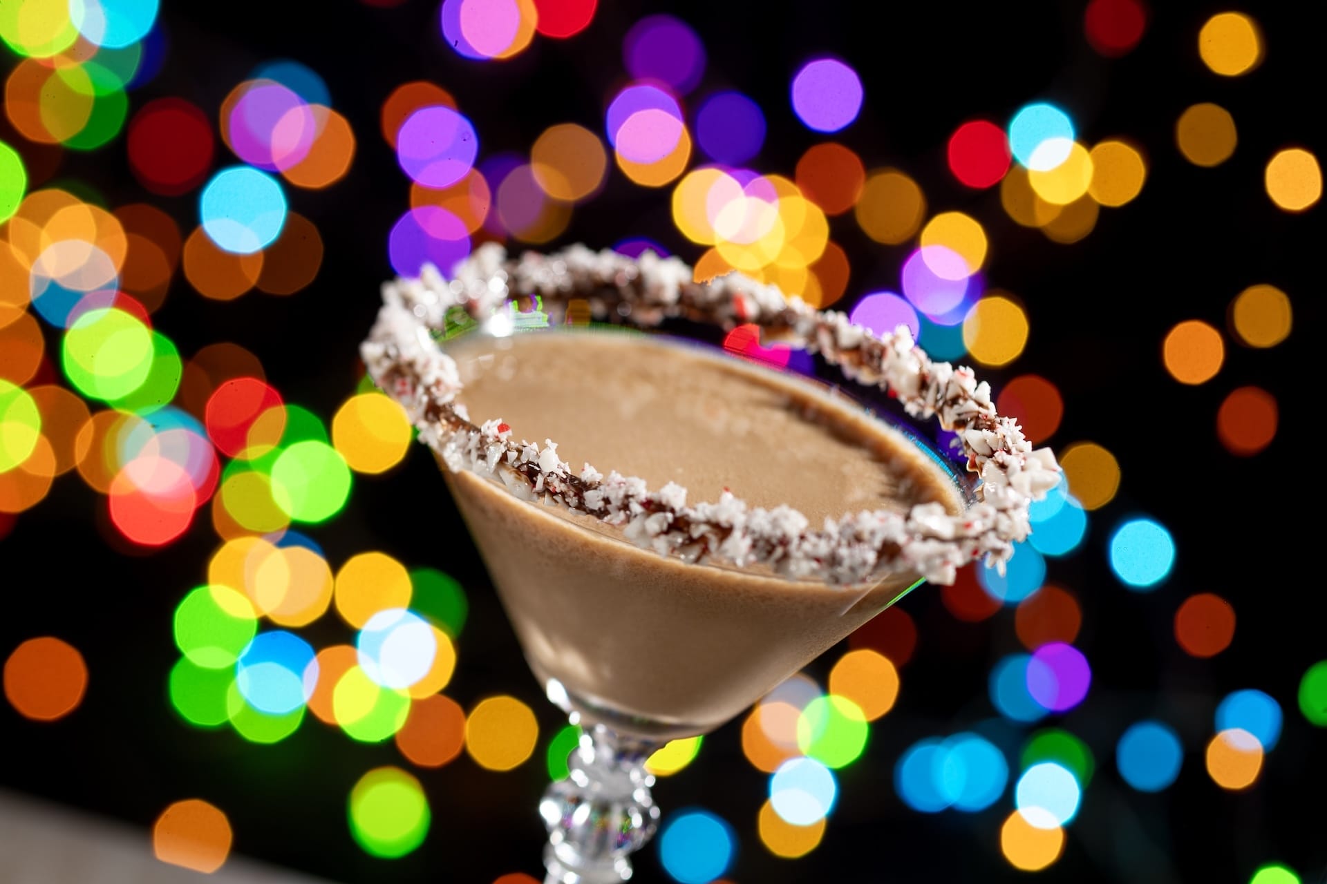 A chocolate martini with a peppermint-rimmed glass, inspired by Disney Jollywood Nights, glows among twinkling park lights.