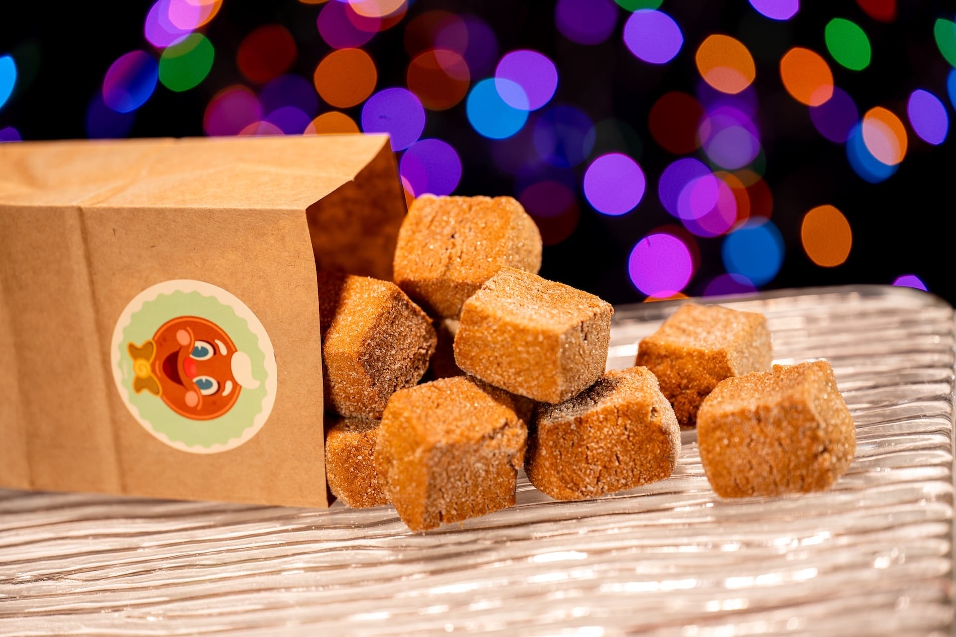 Brown sugar cubes tumble from a gingerbread bag, evoking Disney Jollywood Nights with lights glowing like Main Street, U.S.A.