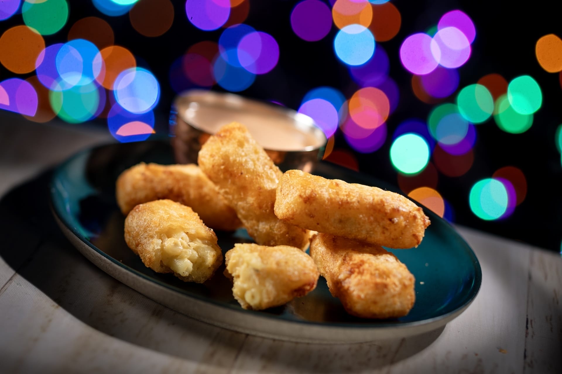 Crispy cheese sticks served on a dark plate with dipping sauce, a tasty treat for 2025 Disney Jollywood Nights park guests.