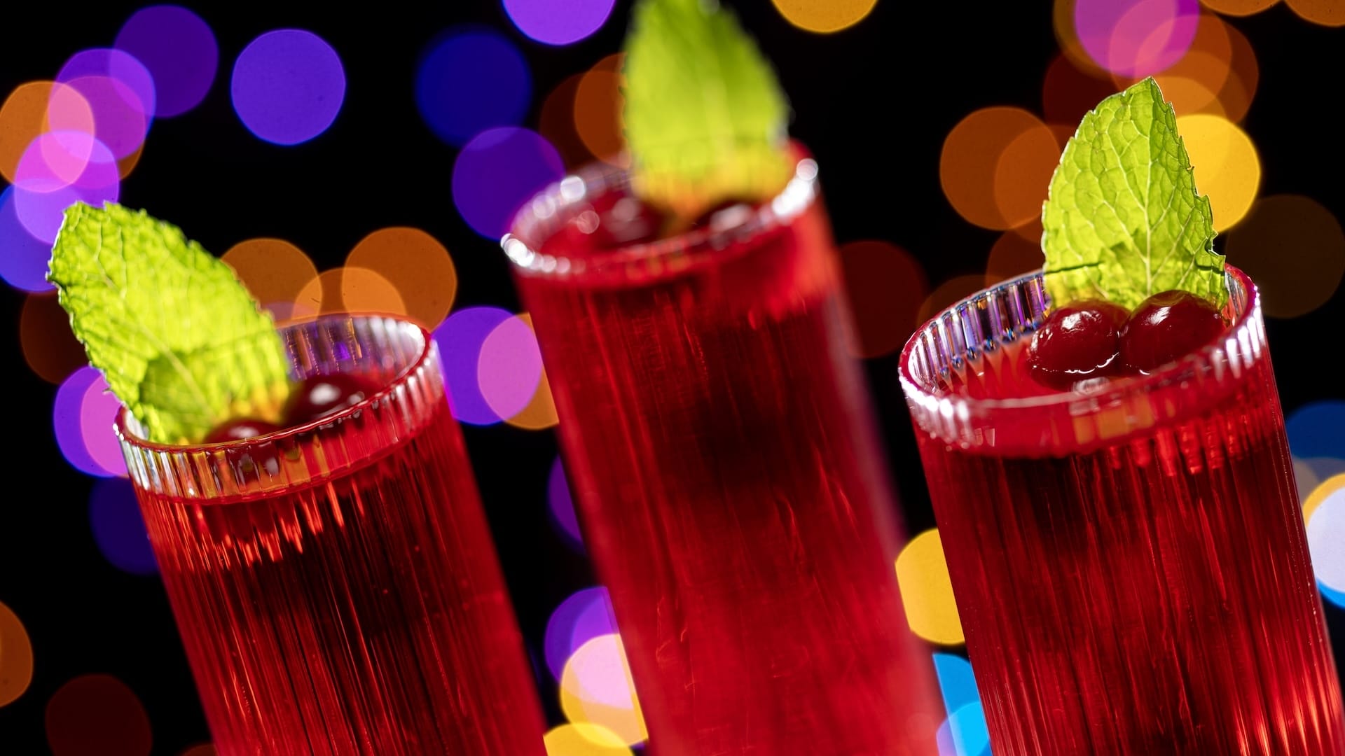 Festive red cocktails with mint leaves for Disney Jollywood Nights, glowing like park treats under twinkling lights—no castle in view.