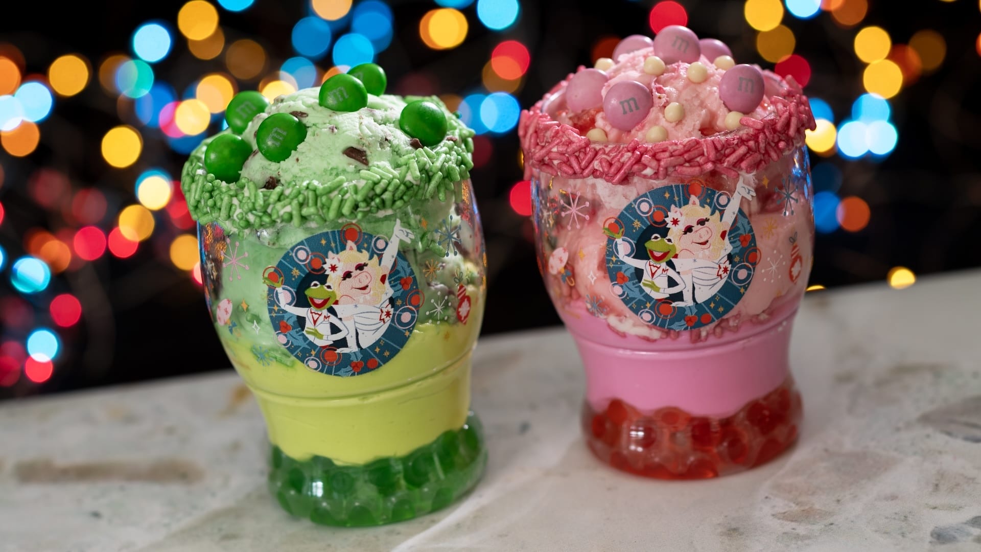 Two vibrant ice cream treats in festive cups, candy-topped—ideal for Disney Jollywood Nights fans at any Disney Park worldwide.