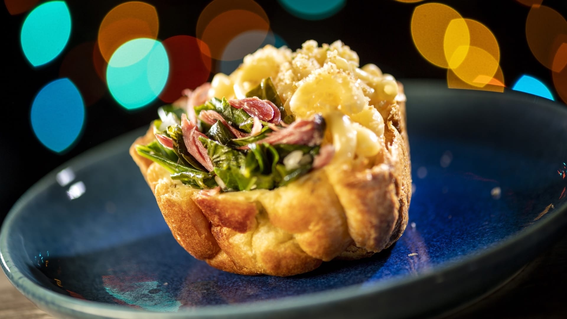 A bread bowl filled with mac and cheese, greens, and ham, featured at Disney Jollywood Nights 2025—exclusive park cuisine.