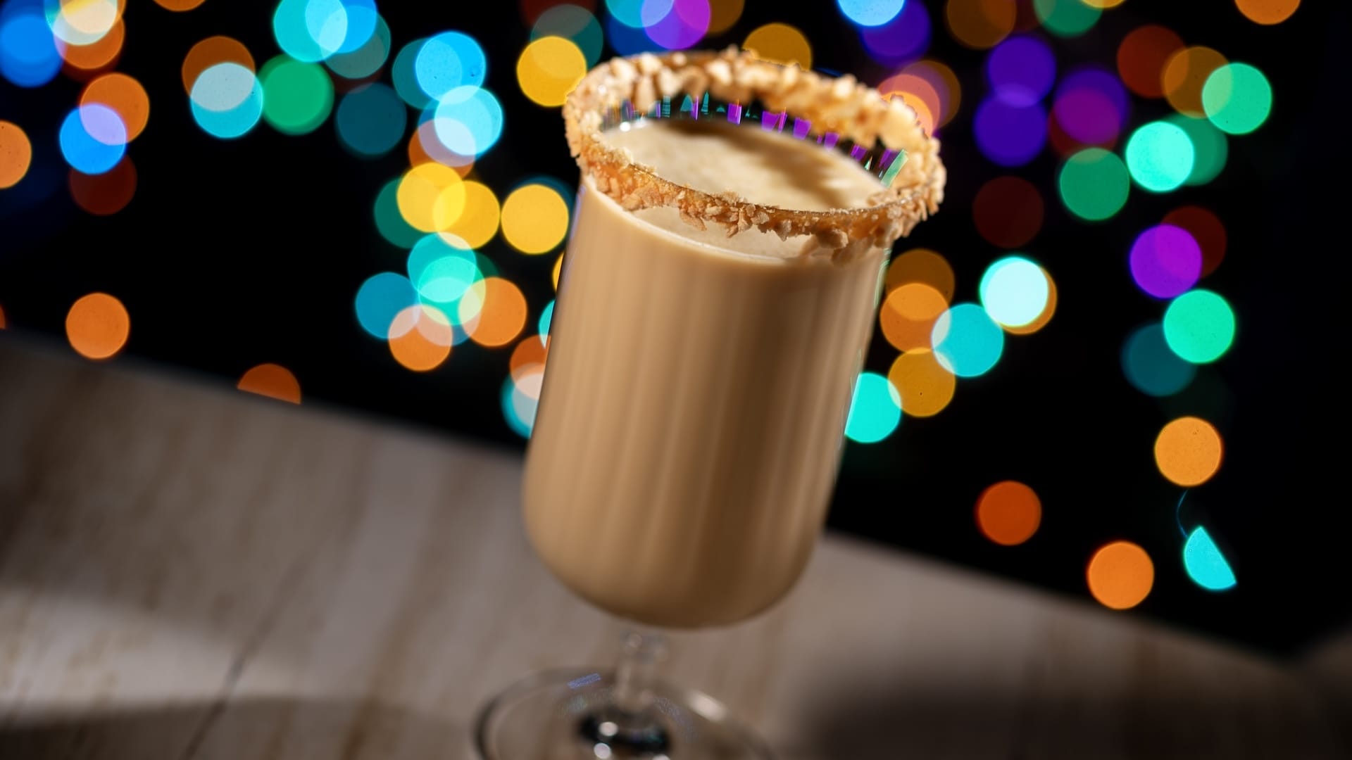 A creamy cocktail in a glass with a crumb-coated rim, showcasing Disney Jollywood Nights 2025; no castle, just festive flair.