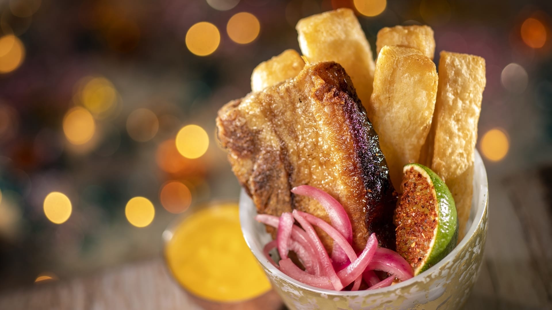 Crispy pork belly with fried yuca, pickled onions, and sauce at Disney Jollywood Nights 2025—delicious park fare.