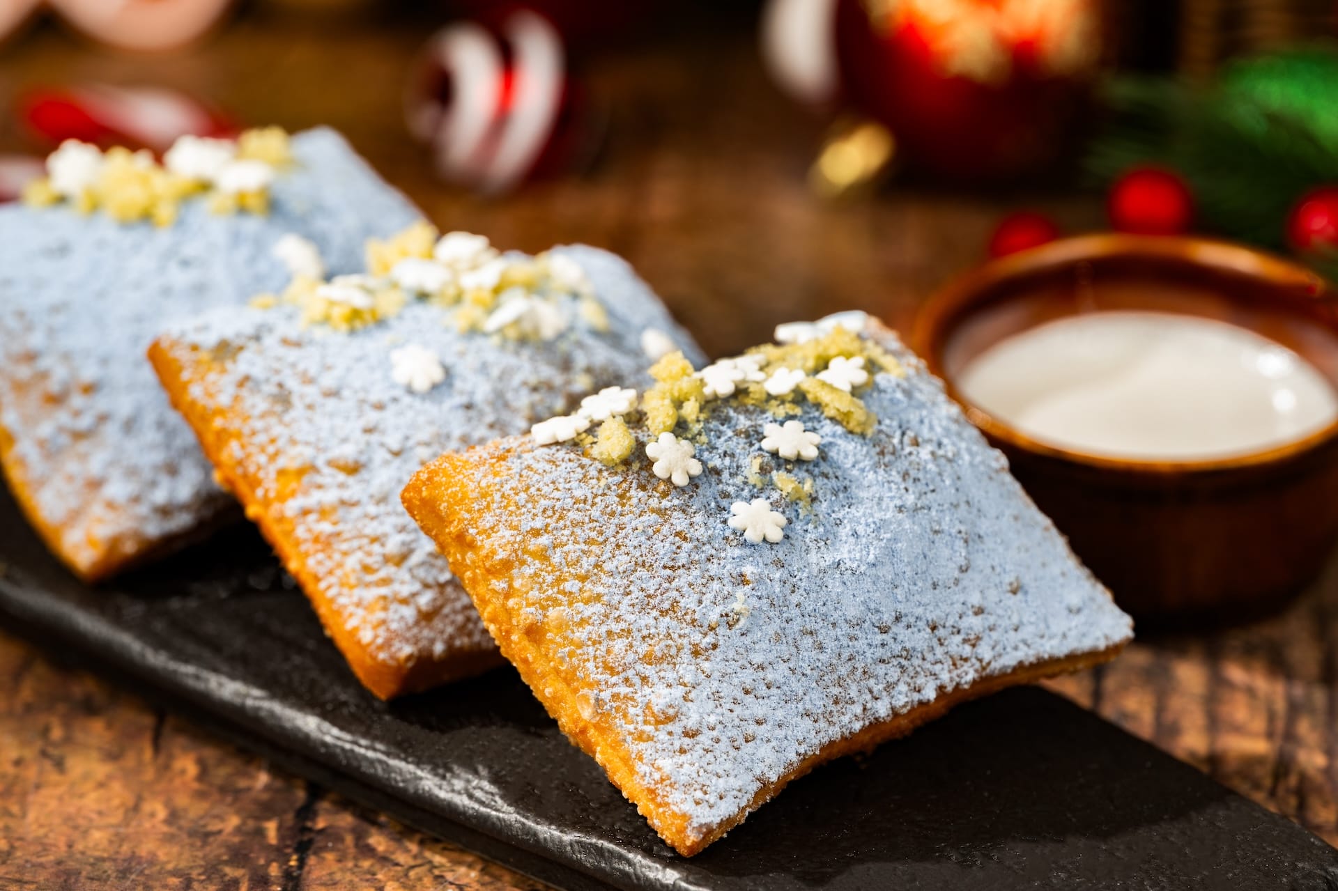 Three powdered beignets with sugar and snowflake sprinkles, a festive holiday treat from Disney Parks' 2025 menu.