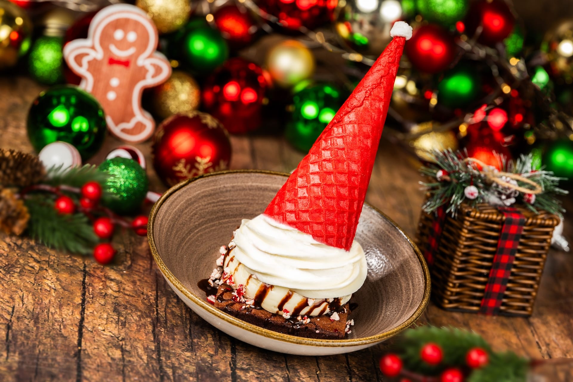 A 2025 holiday dessert with a red Santa hat topping glows at Mickey’s Very Merry Christmas Party in the Disney park setting.