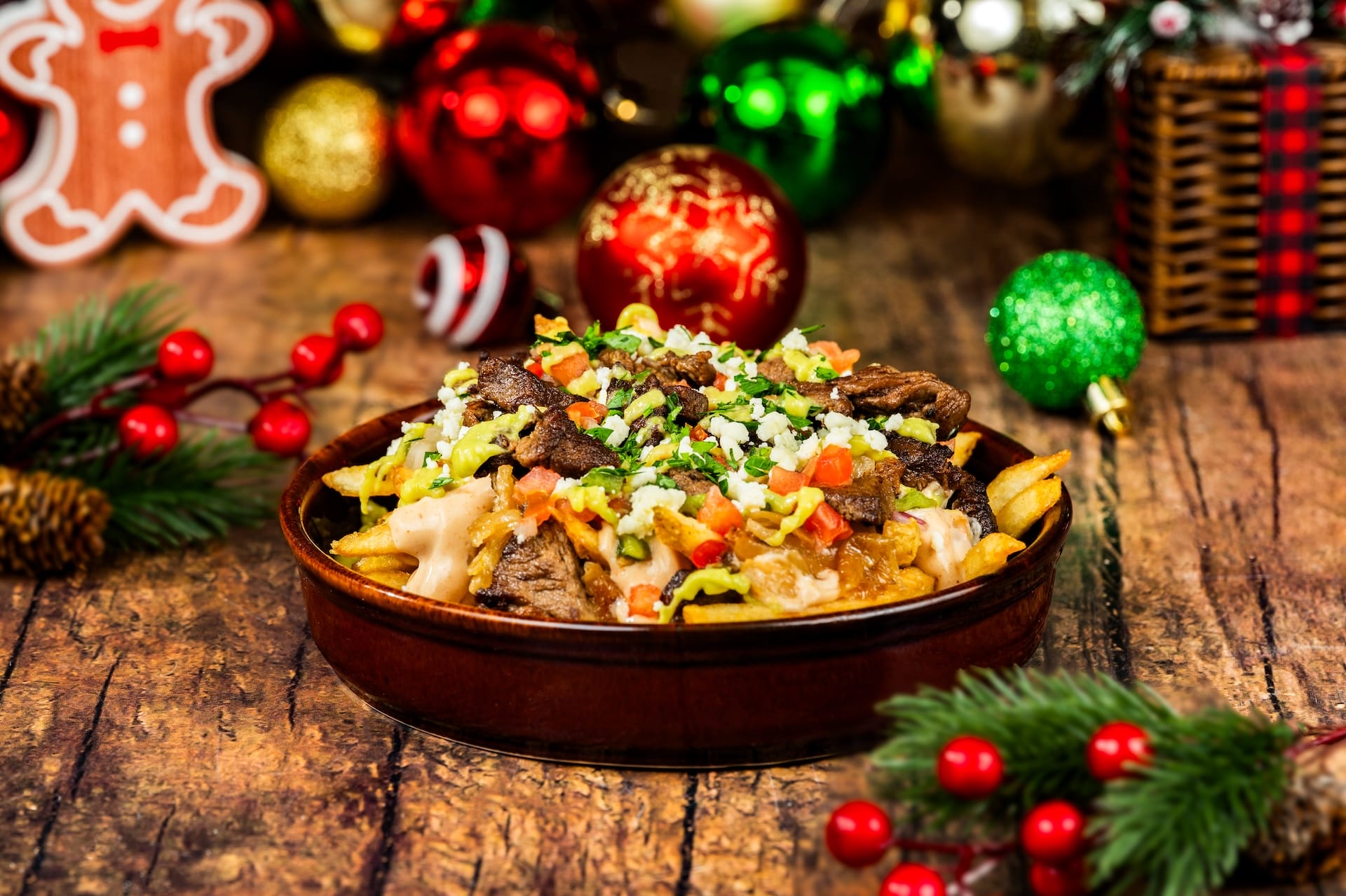 A festive bowl of loaded fries with beef, cheese, and veggies from the 2025 menu, surrounded by Disney park holiday décor.