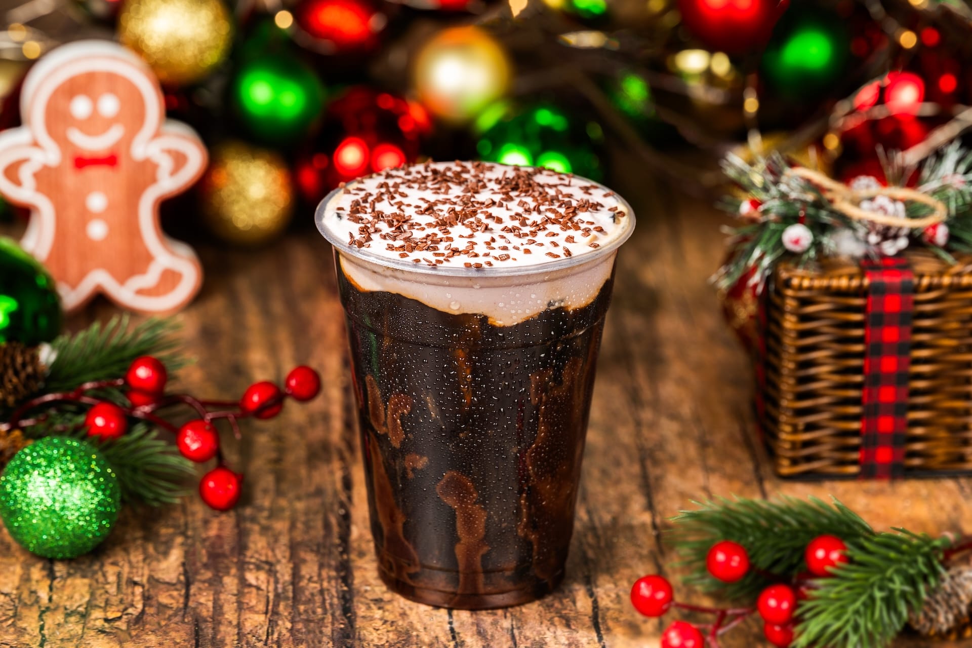 Iced coffee topped with whipped cream and chocolate sprinkles, served with Christmas decor—like treats at Disney Parks during holidays.