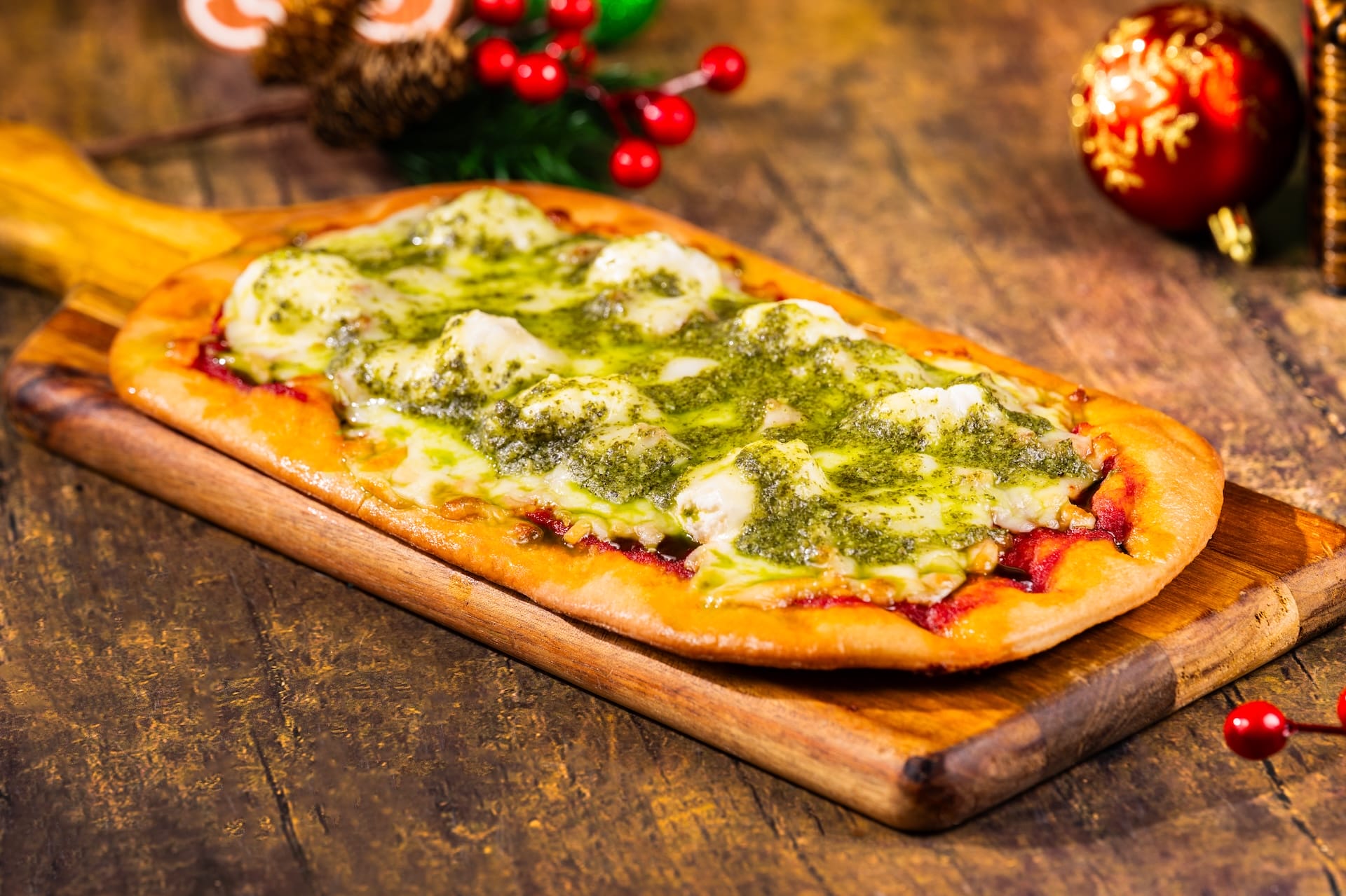 Flatbread pizza topped with golden cheese and green pesto, a festive treat from Mickey’s Very Merry Christmas Party at Walt Disney World.