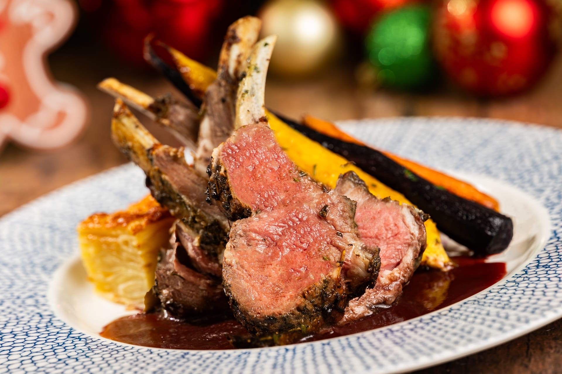 Elegant rack of lamb with roasted carrots, potato gratin, and sauce—festive fare worthy of a celebratory Disney park meal.