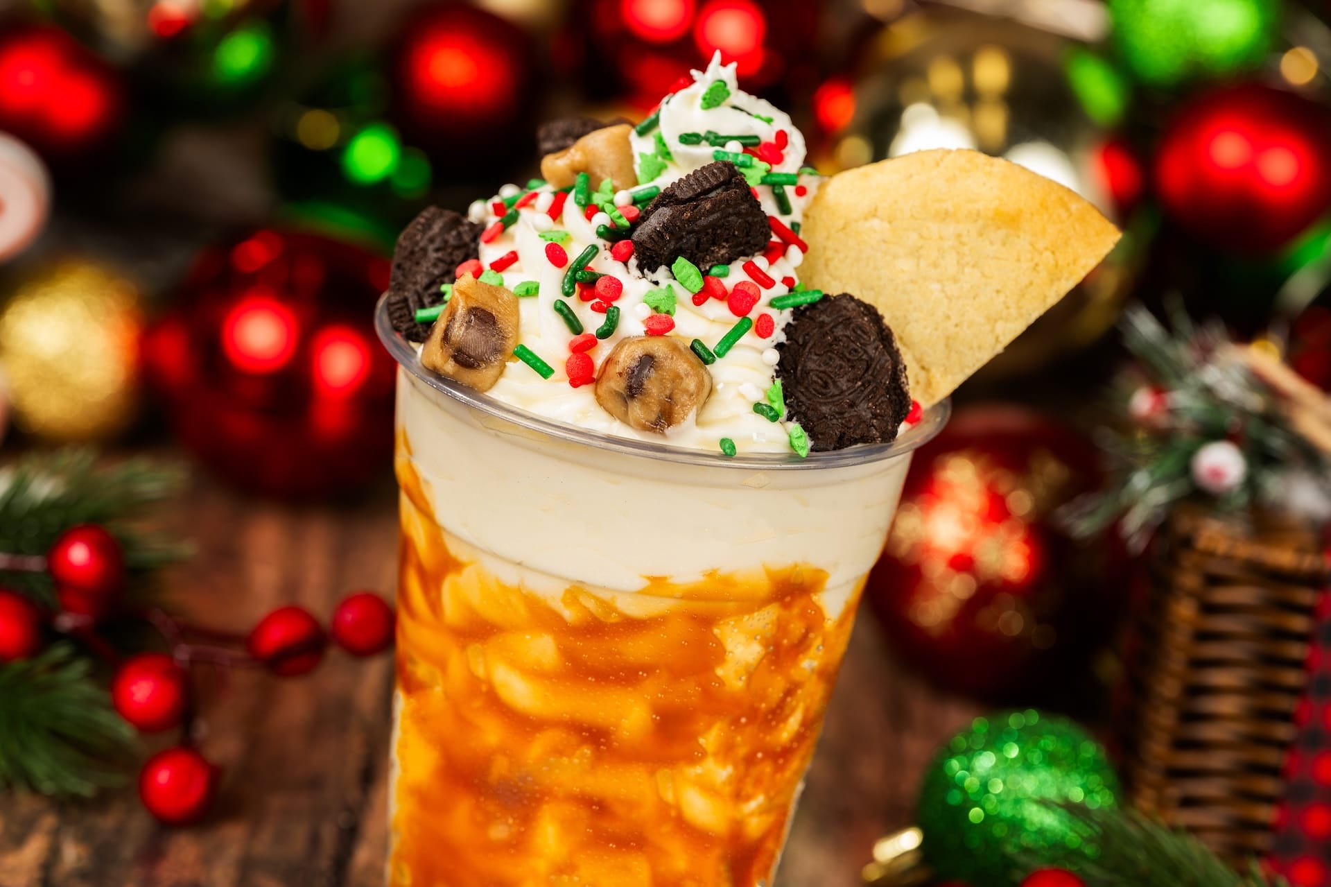 A magical holiday caramel sundae from a Disney park, crowned with whipped cream, colorful sprinkles, cookies, and a cookie wedge.
