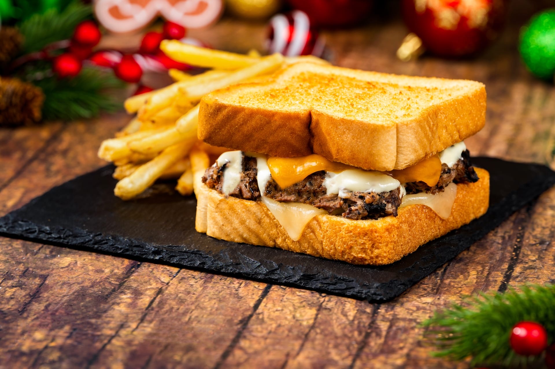 A holiday sandwich with melted cheese and beef on toasted bread with fries, a festive 2025 Disney Parks menu item.