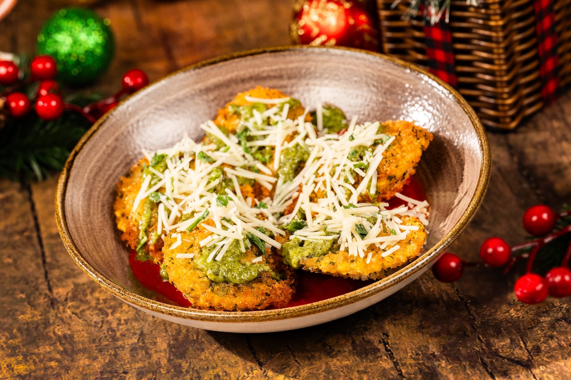 A bowl of breaded ravioli topped with pesto and cheese, served on a rustic table, inspired by a Disney Parks Holiday menu.