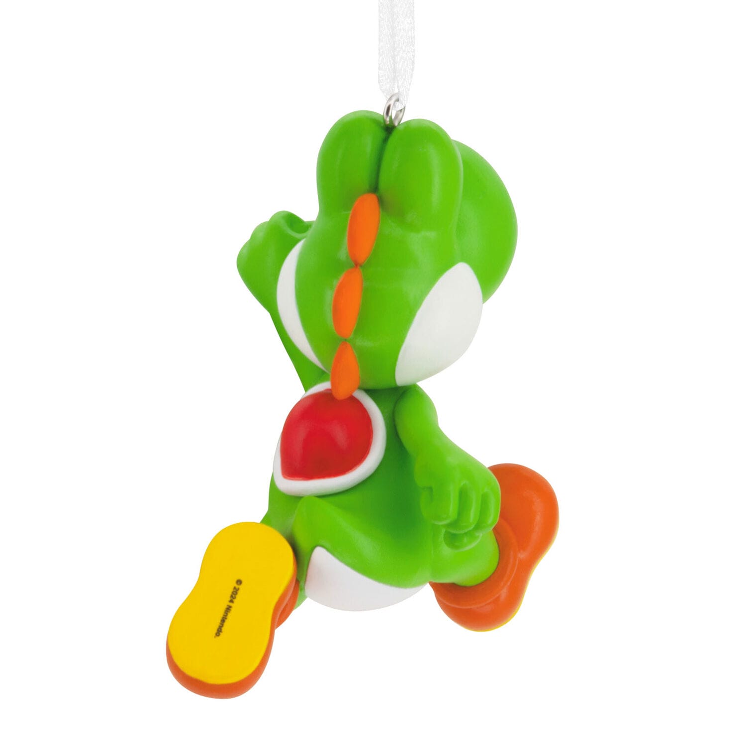 A green dinosaur ornament with orange shoes and spikes, hanging by a white ribbon