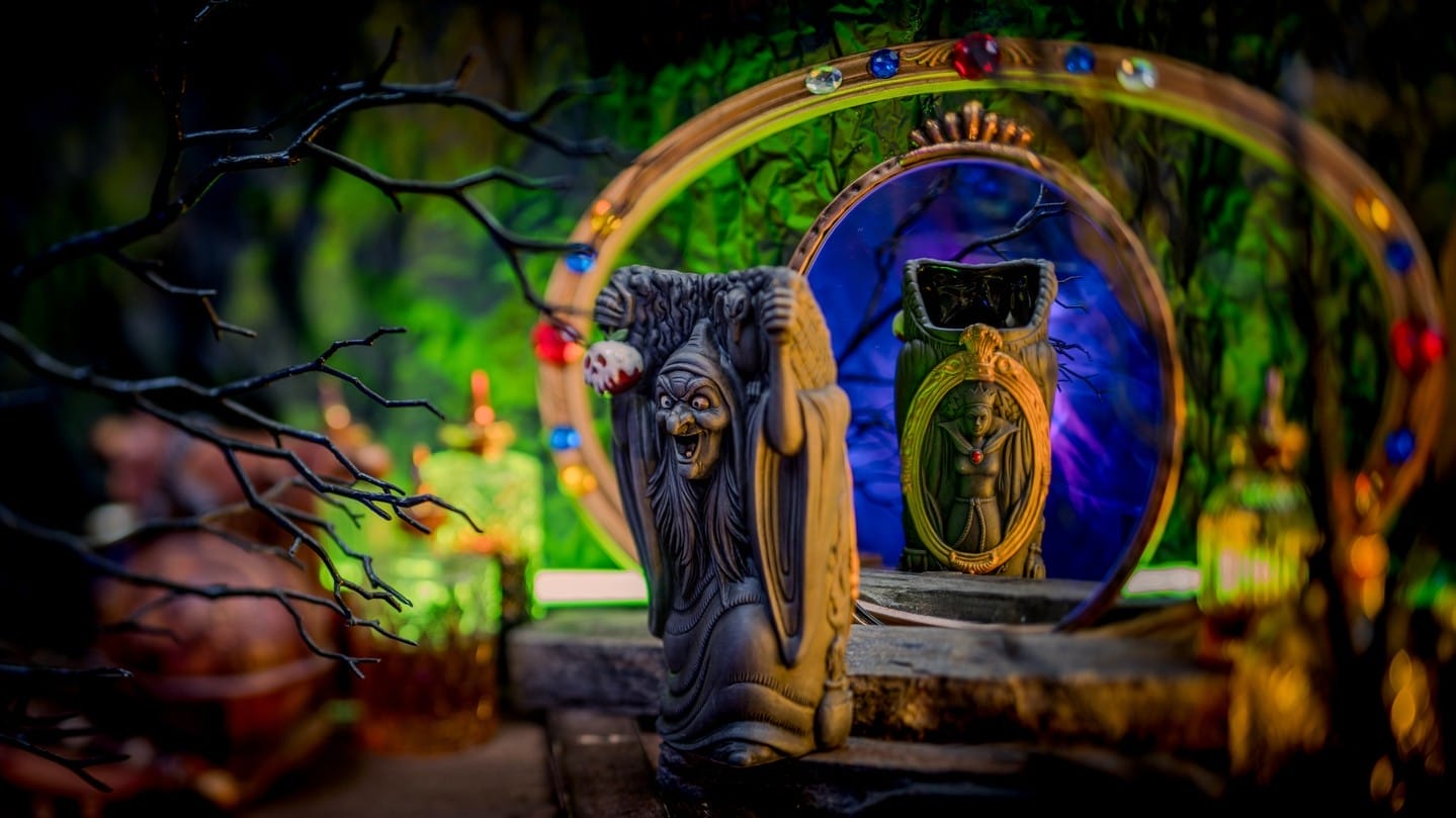 A spooky witch figurine faces a jeweled mirror, echoing the chilling style of the Evil Queen Mug at Disneyland Hotel.