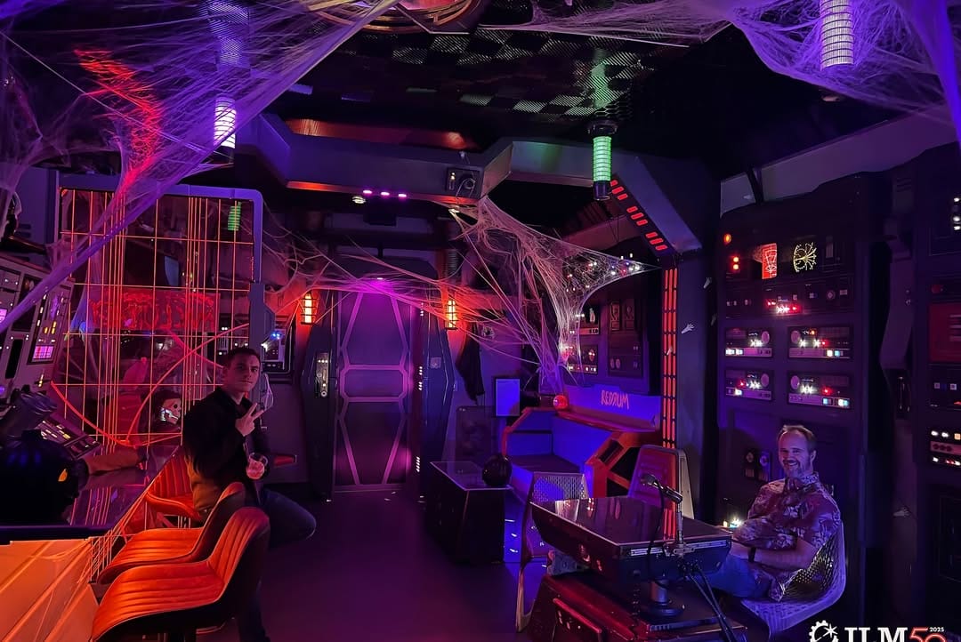 Two people in a Star Wars-themed room with purple lights and Halloween spider webs, reminiscent of Disney’s Galaxy’s Edge.