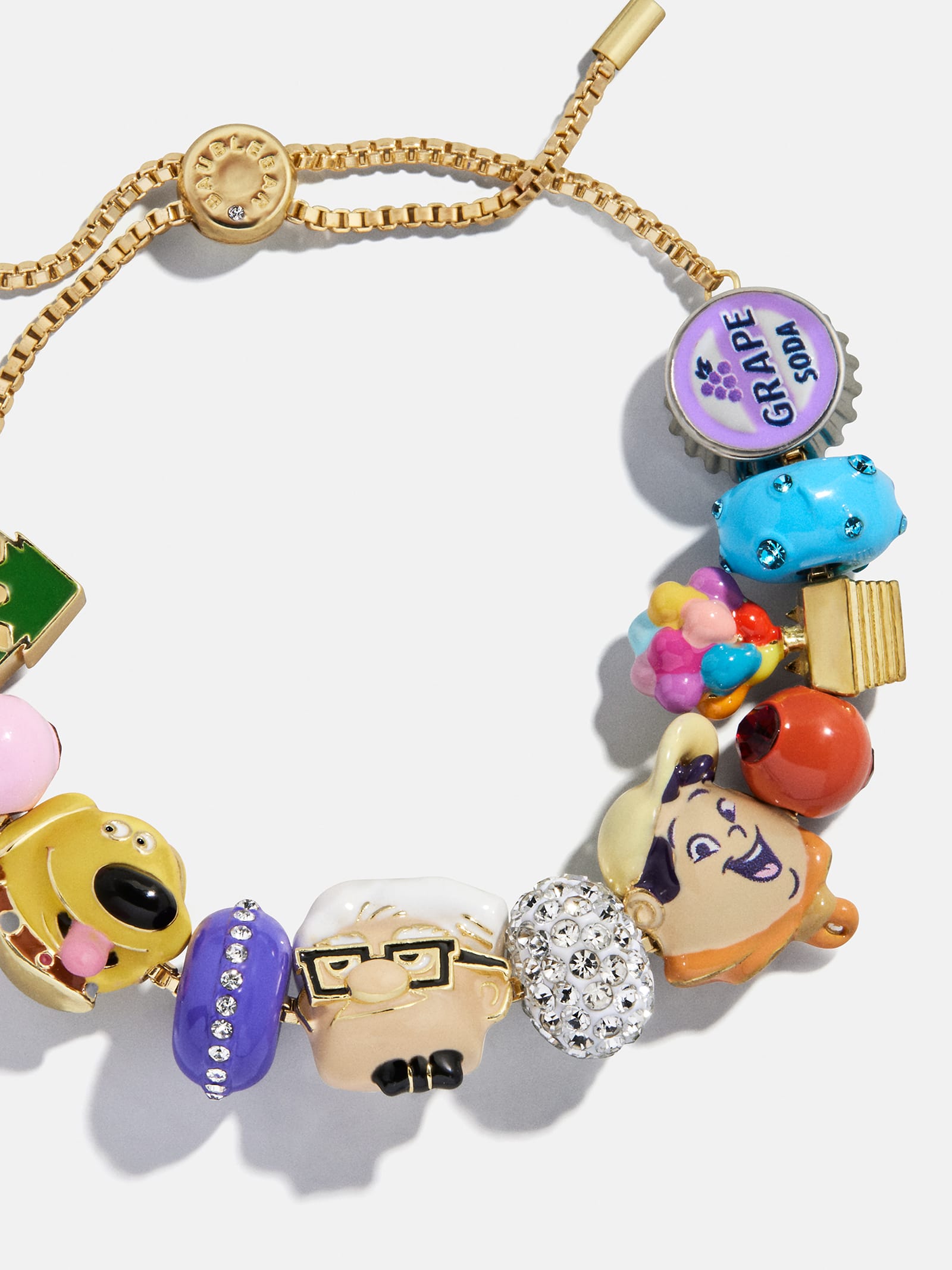 Gold bracelet featuring colorful Pixar "Up" charms, grape soda badge, sparkling beads—evokes whimsy found in Disney Parks.
