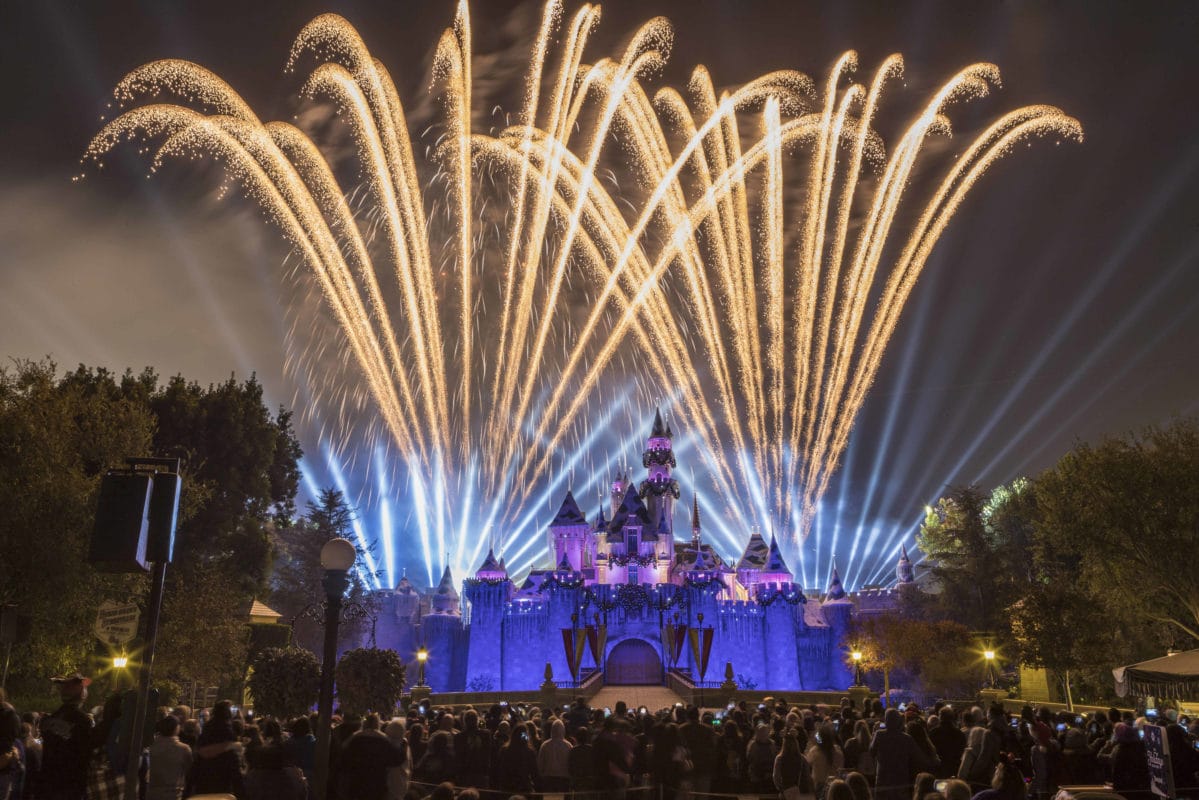 Crowd enjoys fireworks and lights above Disneyland’s Sleeping Beauty Castle, which is smaller than the grander Cinderella Castle in Florida.