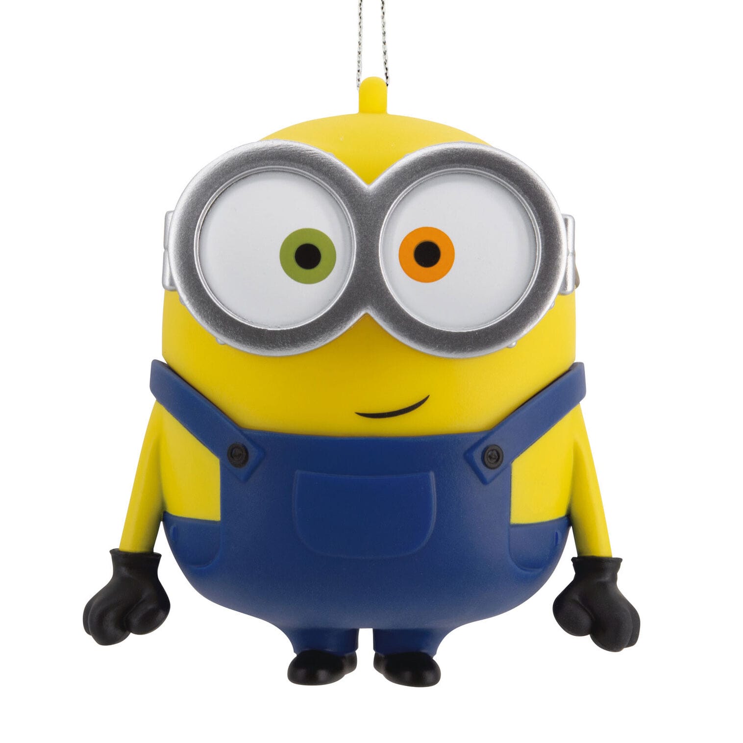 A yellow Minion ornament from Hallmark Ornaments with mismatched eyes, blue overalls, and a small smile