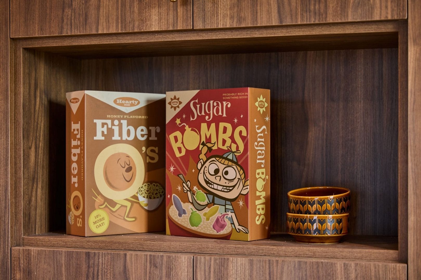 Two colorful cereal boxes and a patterned orange cup on a shelf, with bold style reminiscent of Incredibles 2 decor at Disney parks.