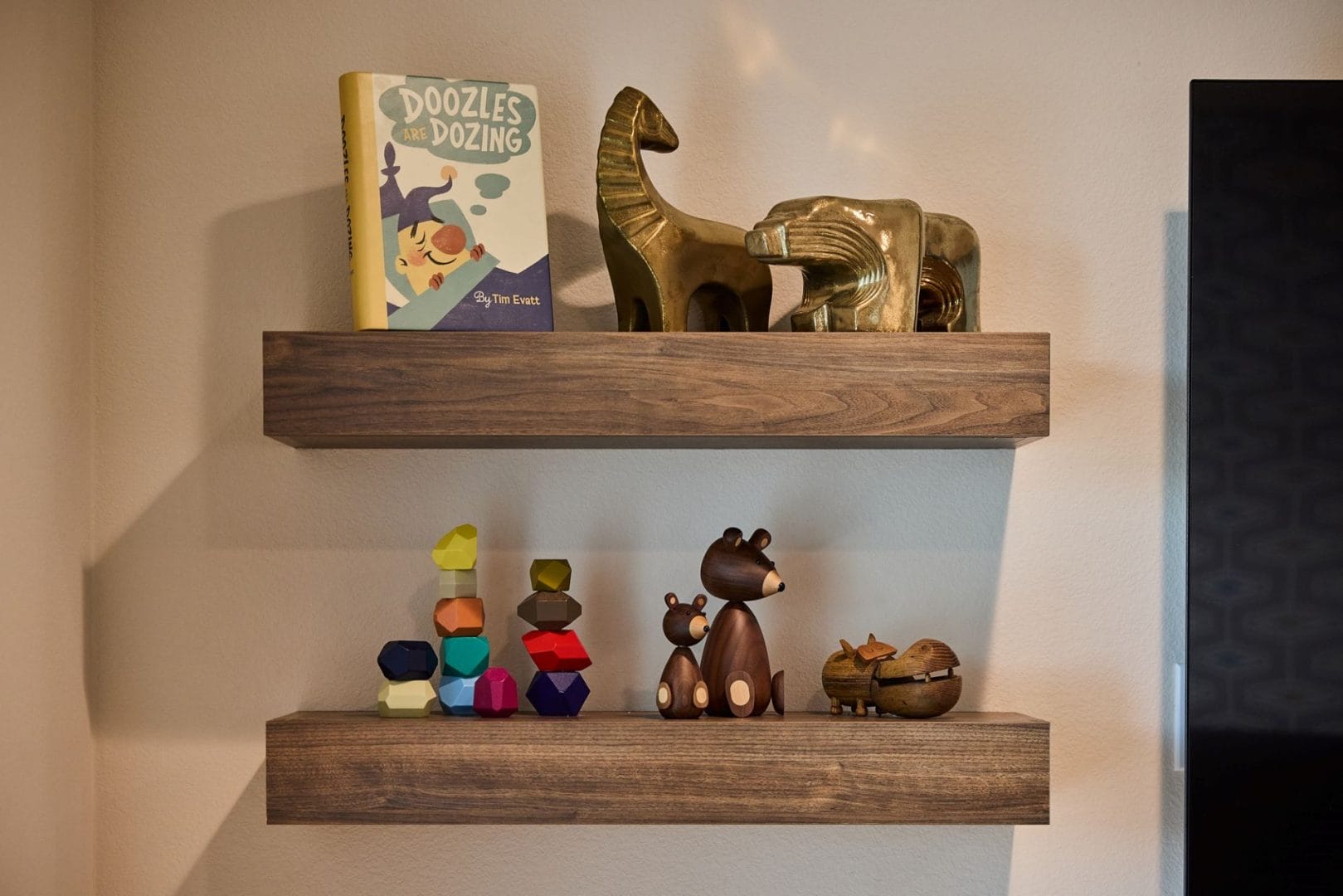 Two wooden shelves show a children’s book, golden horse figures, colorful blocks, and Incredibles 2 figurines from Disney Parks.