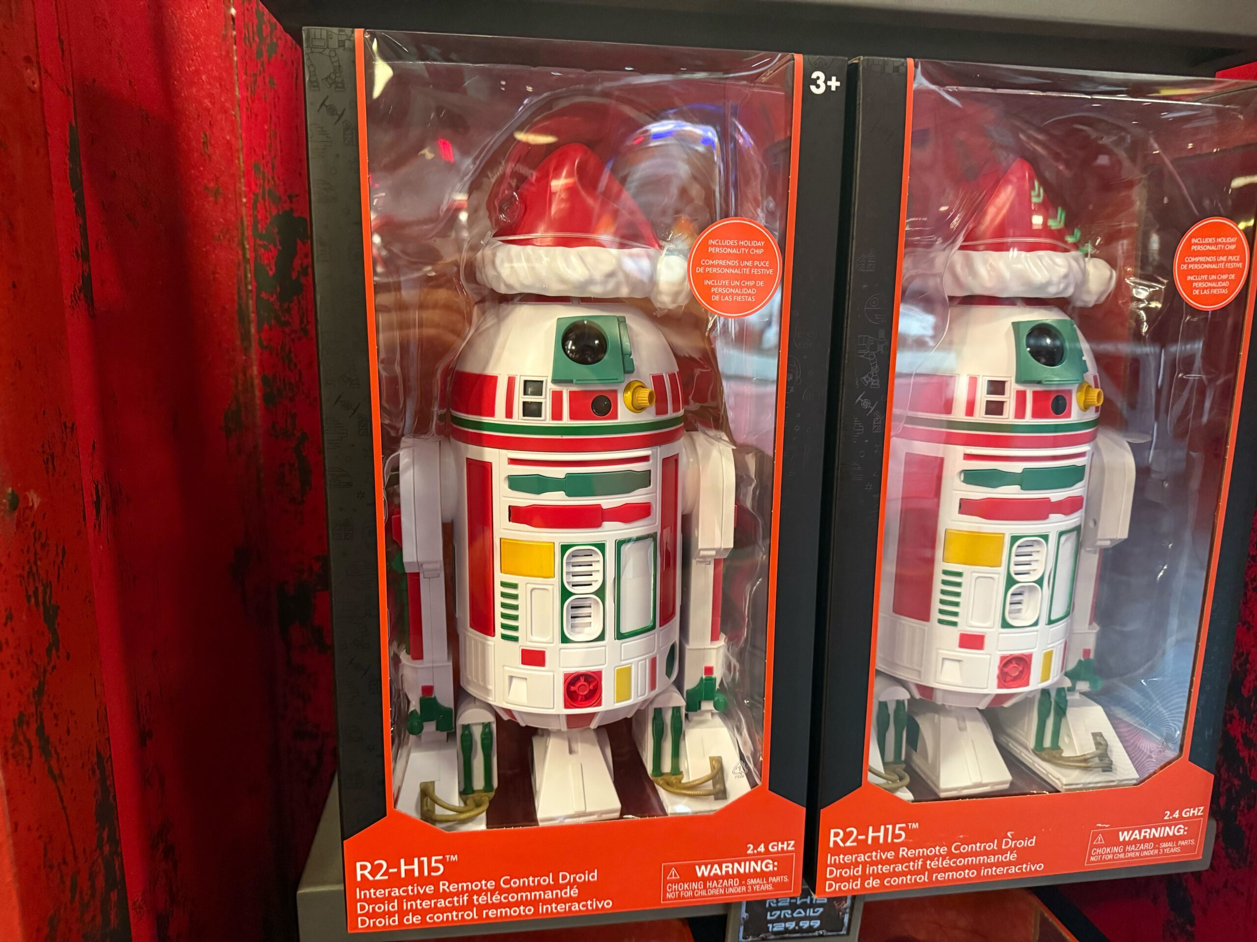 R2-H15 droid toys in festive red and green, part of the 2025 Disneyland Christmas merchandise, wear Santa hats on display.