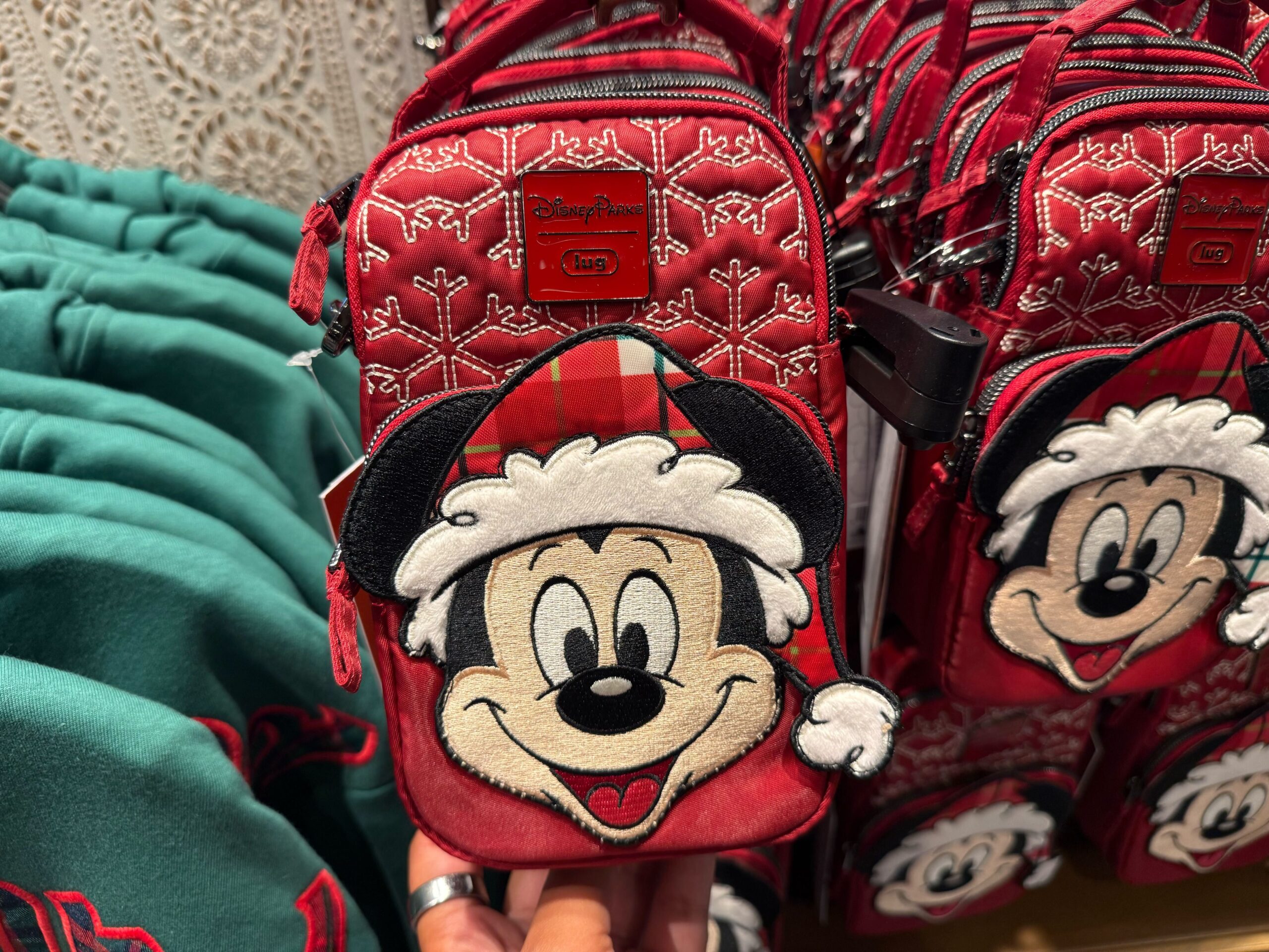 A red holiday bag from Disneyland Christmas Merchandise features Mickey in a Santa hat and snowflake patterns.