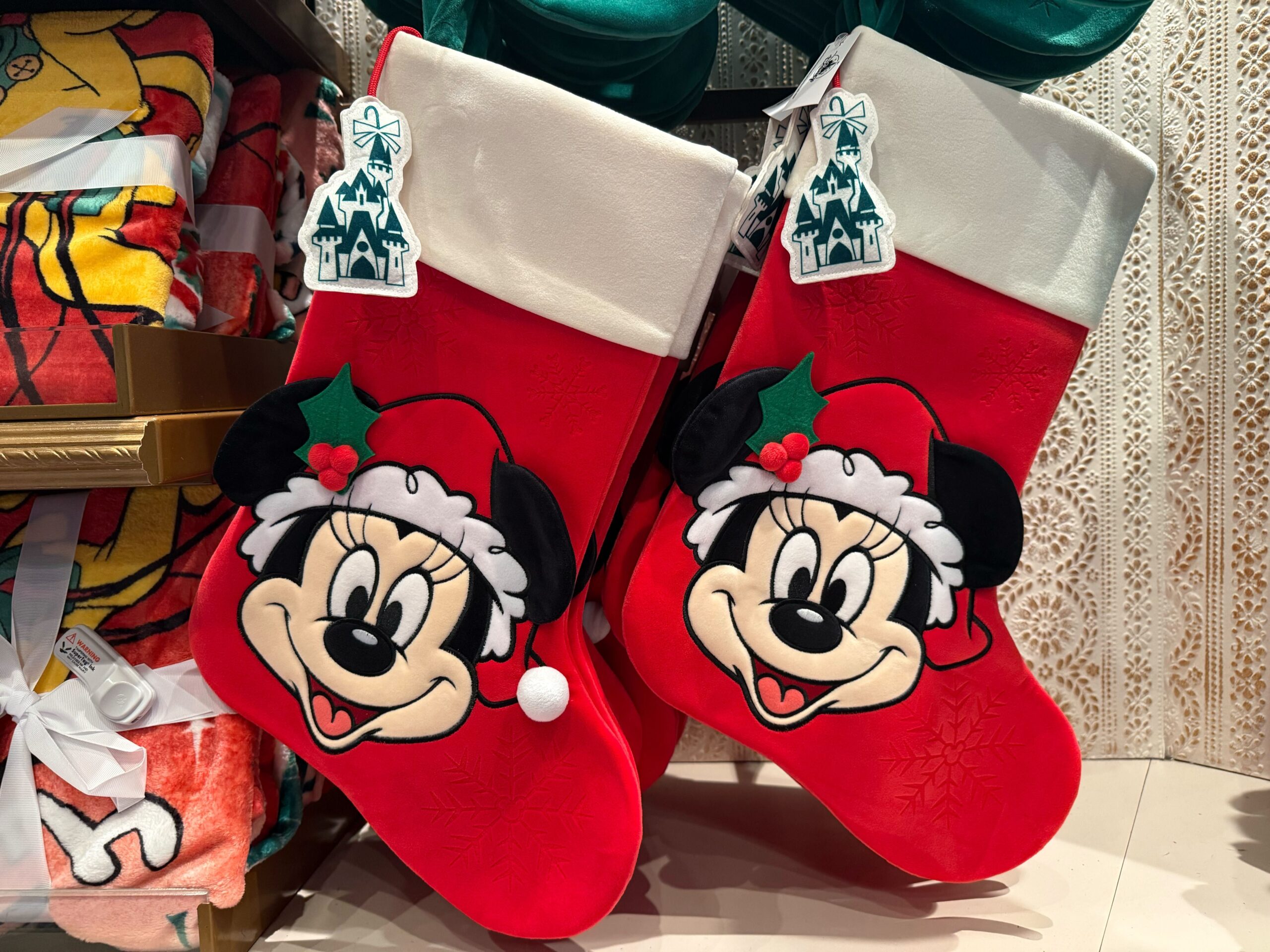 Two red Disneyland Christmas Merchandise stockings with Mickey Mouse faces hang side by side in a 2025 store display.