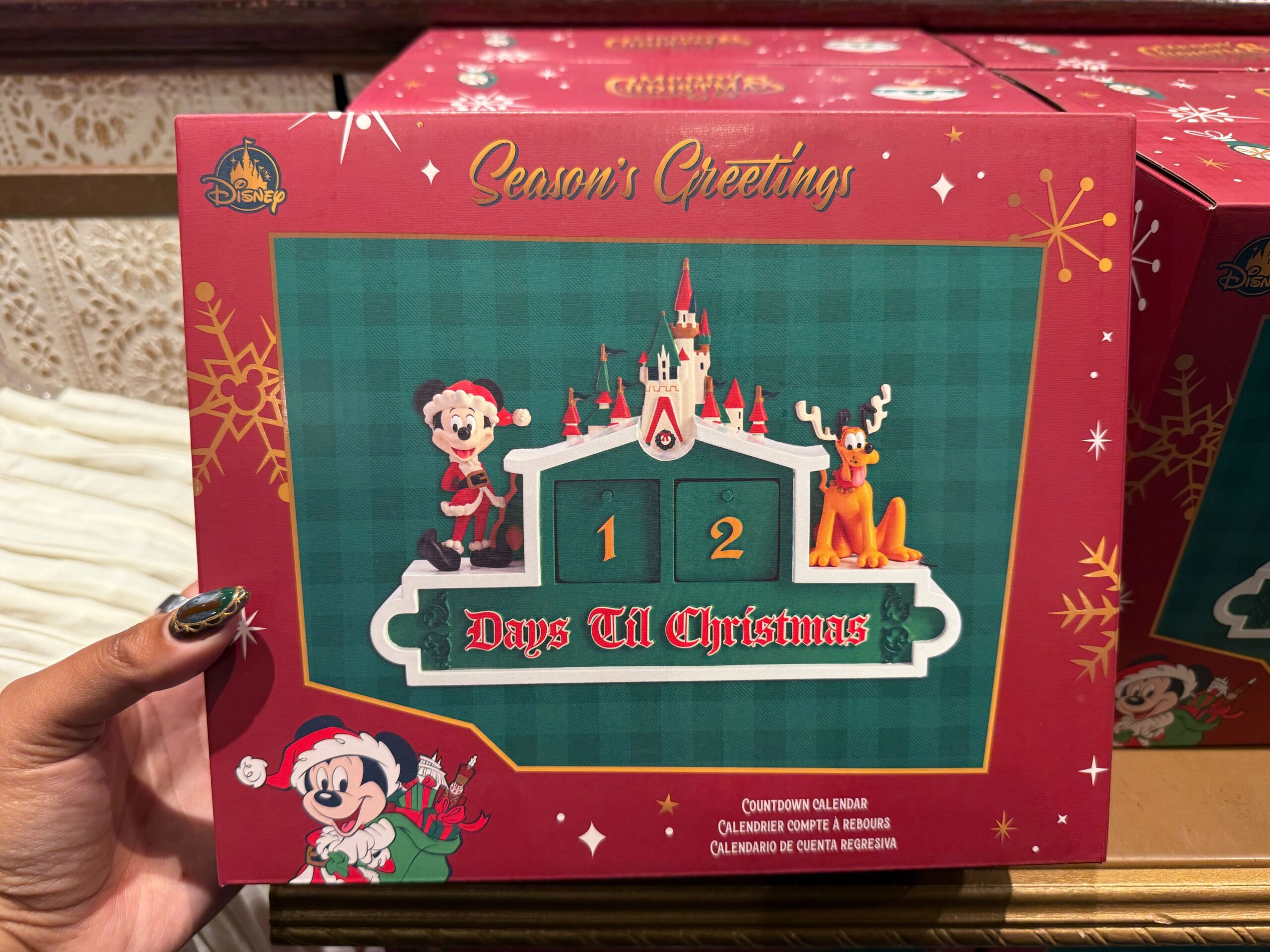 A hand holds a Disneyland merchandise 2025 countdown calendar with Minnie Mouse, a castle, and a reindeer.