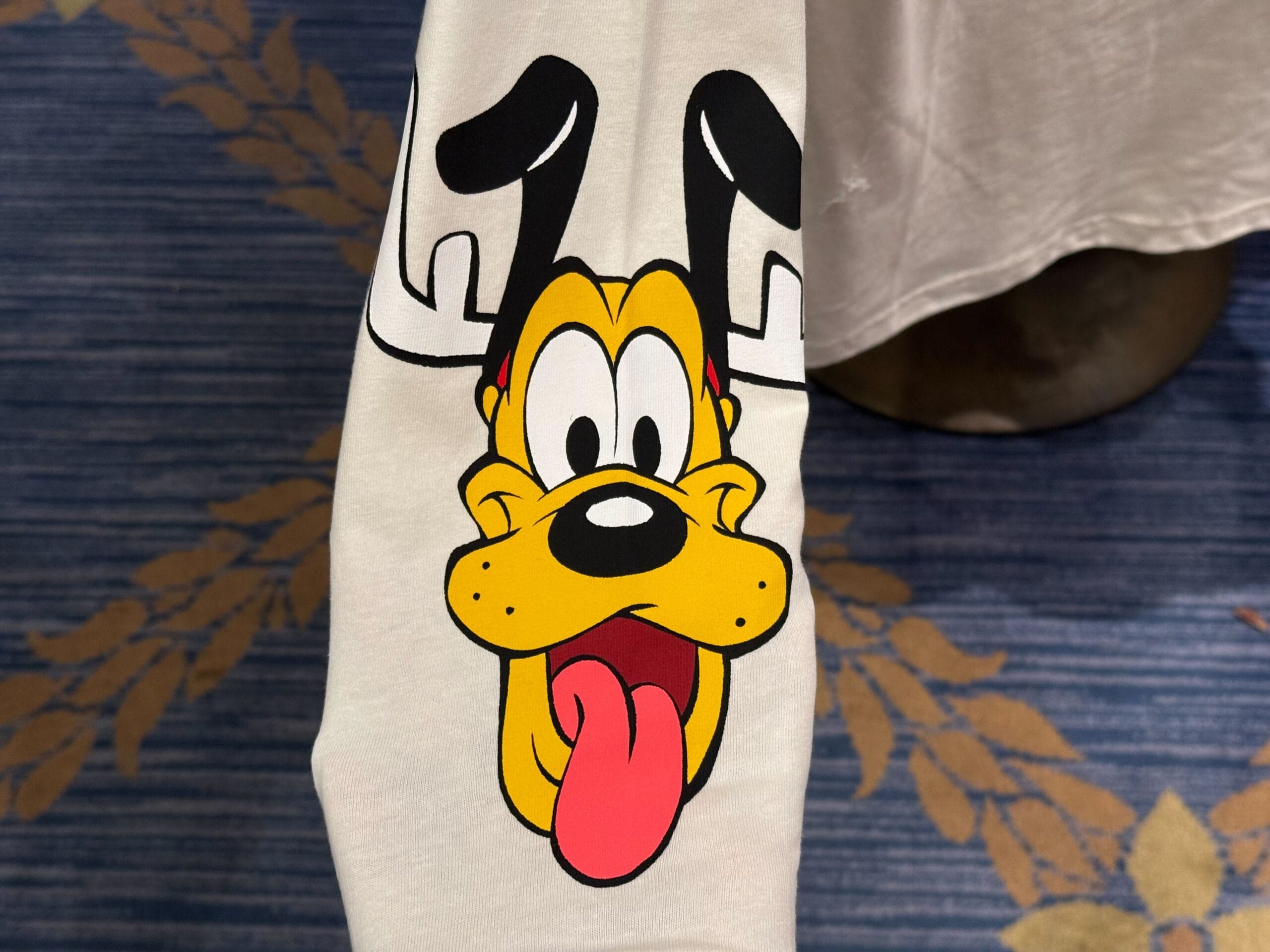 Cartoon dog with floppy ears and tongue out featured on 2025 Disneyland Christmas merchandise sleeve.