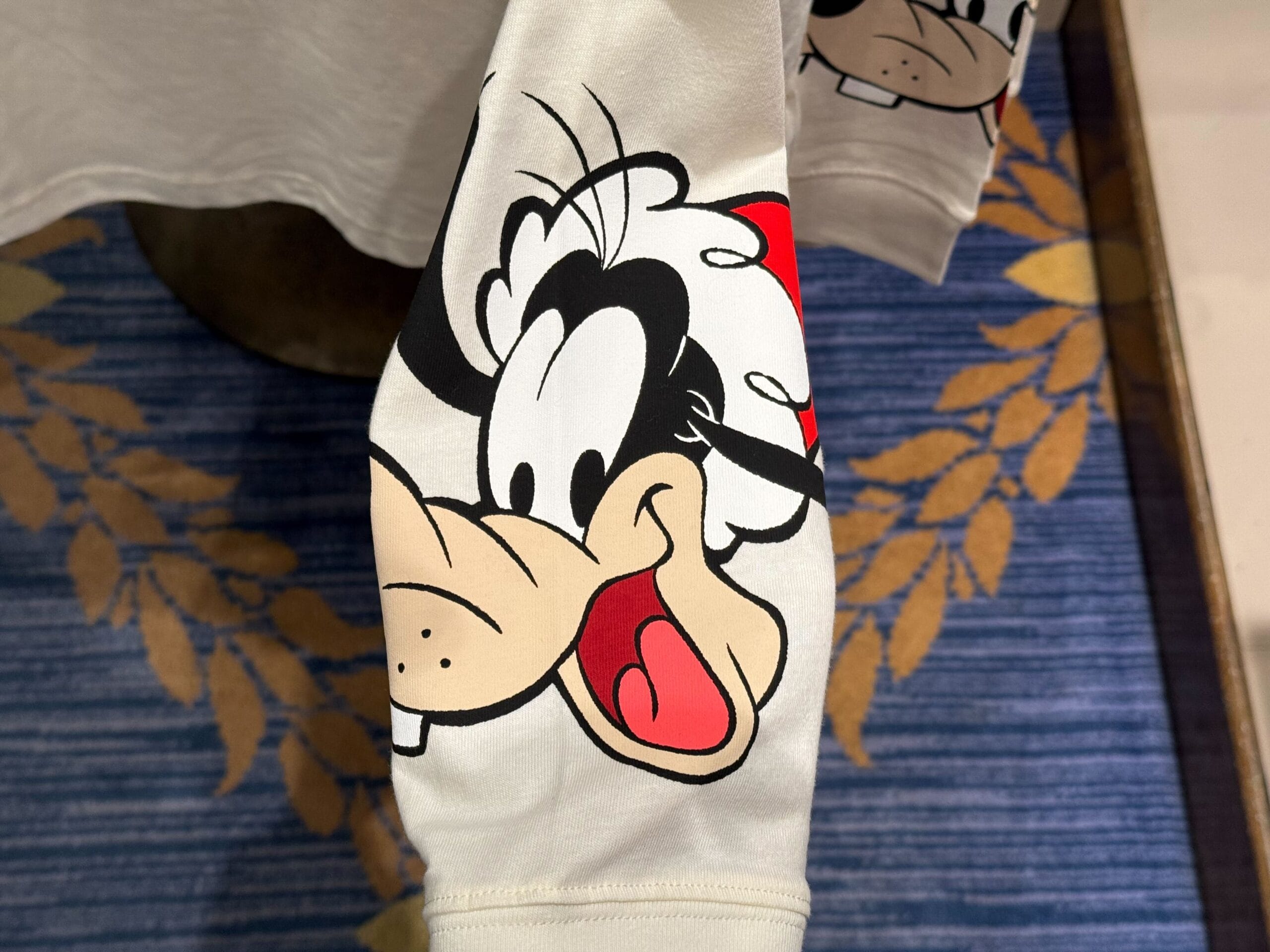 Cartoon character Goofy’s face printed on a white sleeve, part of 2025 Disneyland Christmas merchandise.