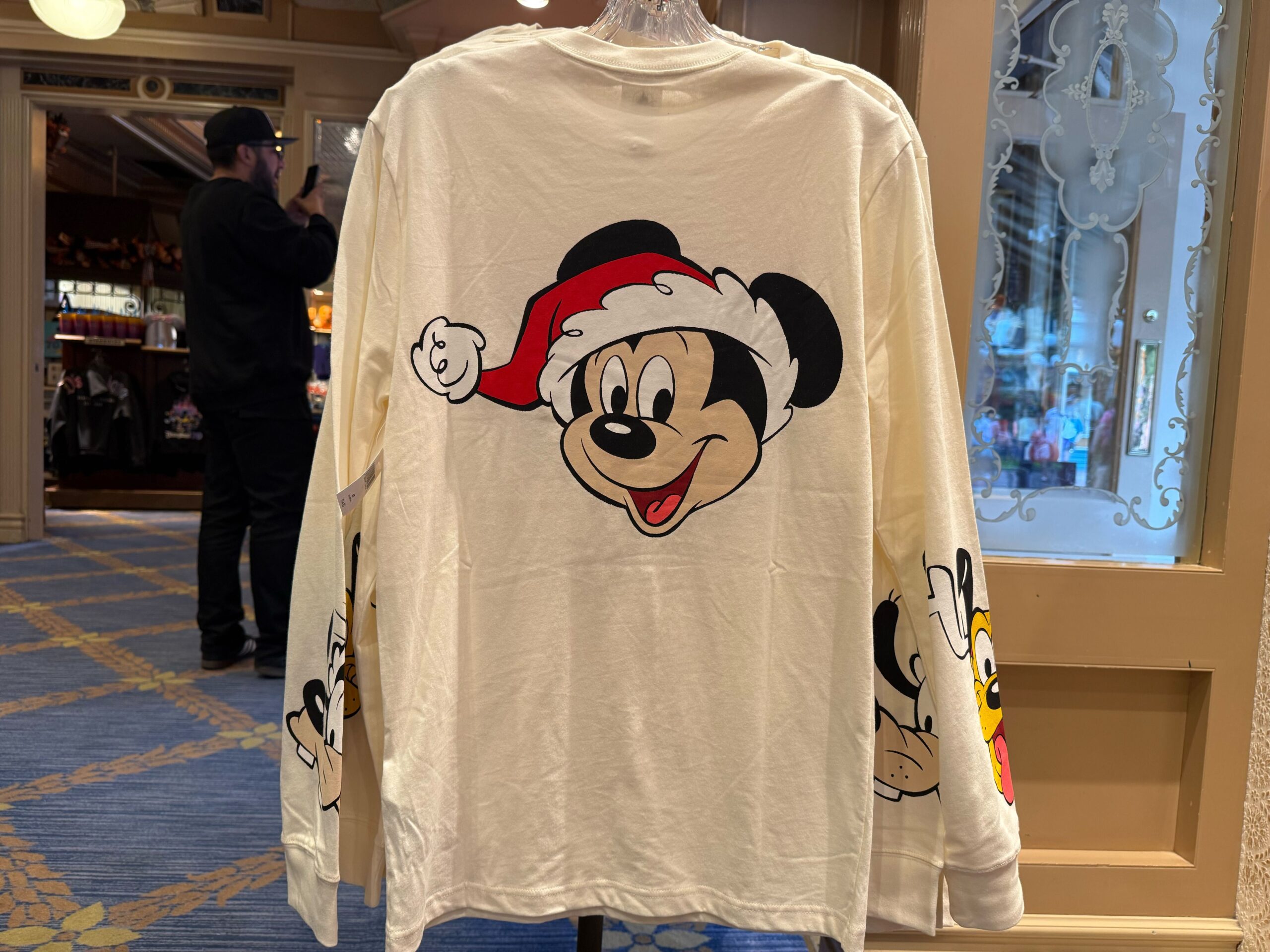 Long-sleeve shirt with Mickey Mouse in a Santa hat, part of 2025 Disneyland Christmas merchandise in store.