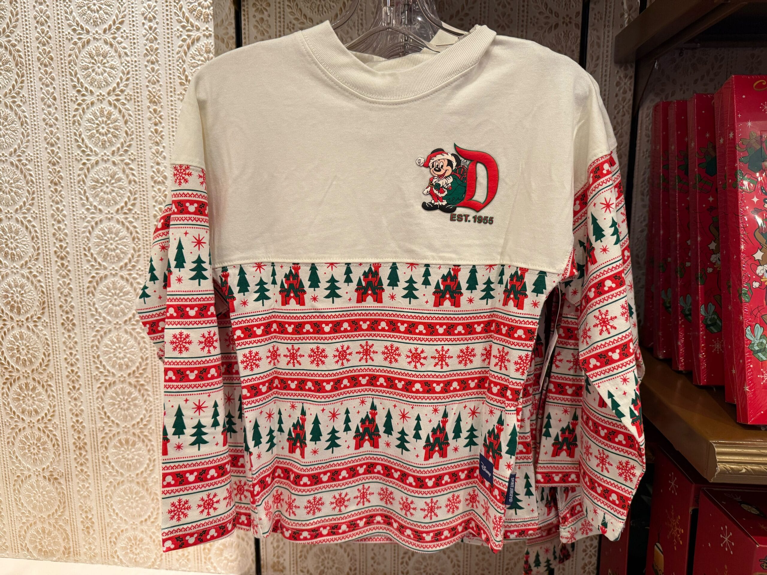 Cream and red holiday shirt featuring Christmas trees, snowflakes, and a 2025 Disneyland Mickey Mouse "D" patch on the chest.
