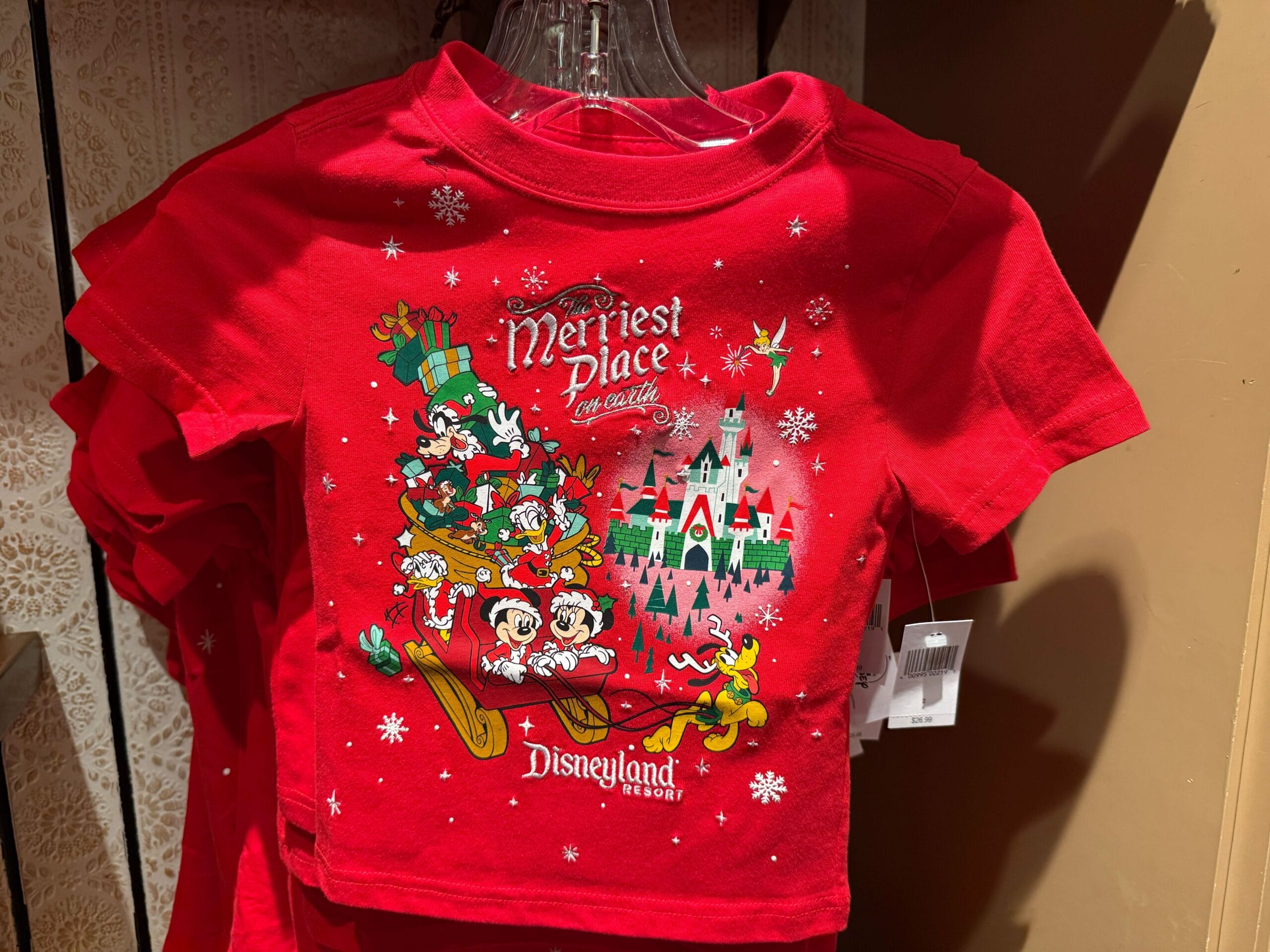 Red Disneyland Christmas merchandise shirt with Mickey, Minnie, Donald, Goofy, Pluto on a sleigh, castle, and snowflakes.