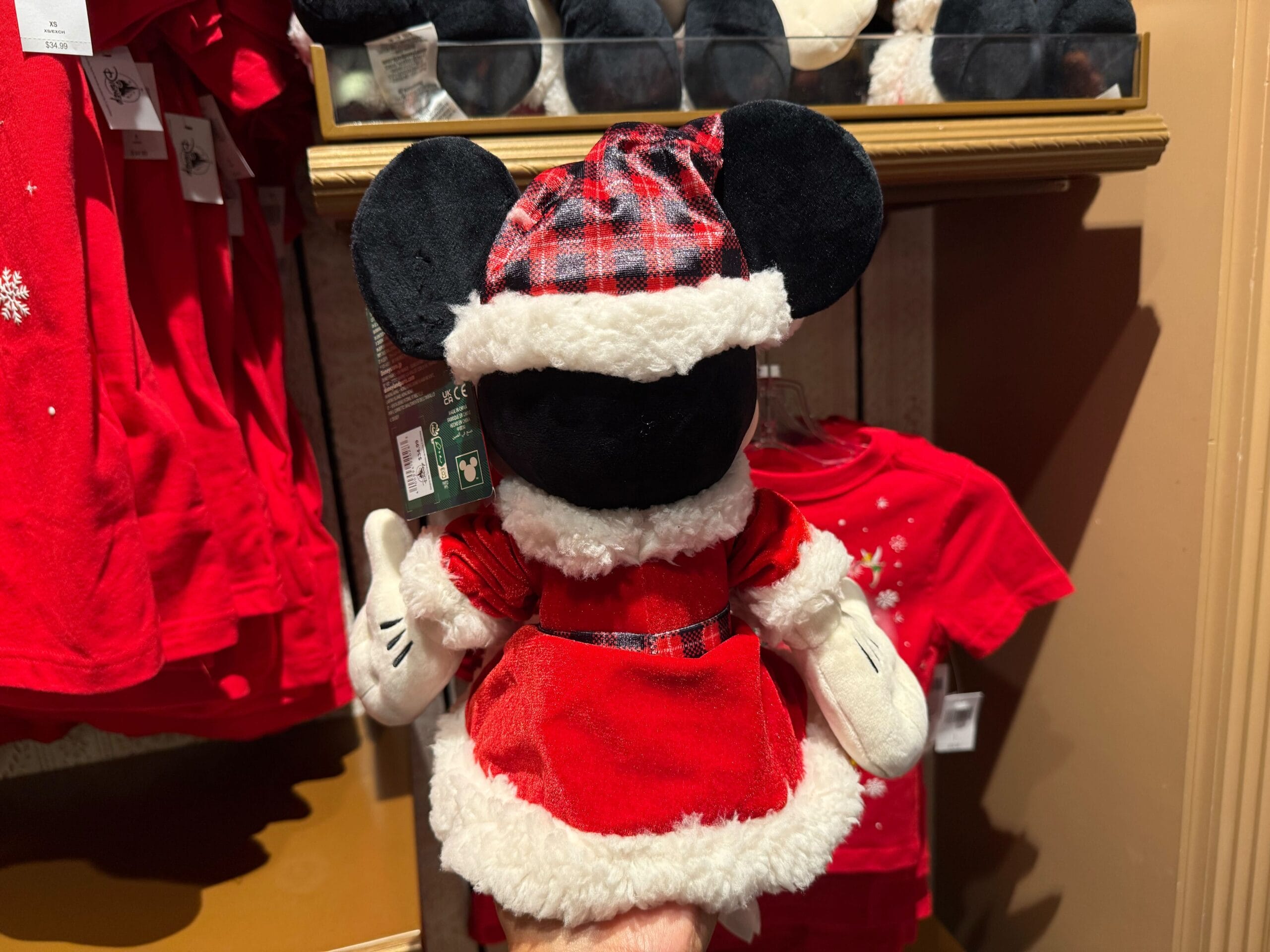 Plush toy mouse in a red plaid Santa hat and dress, part of the 2025 Disneyland Christmas Merchandise on display.