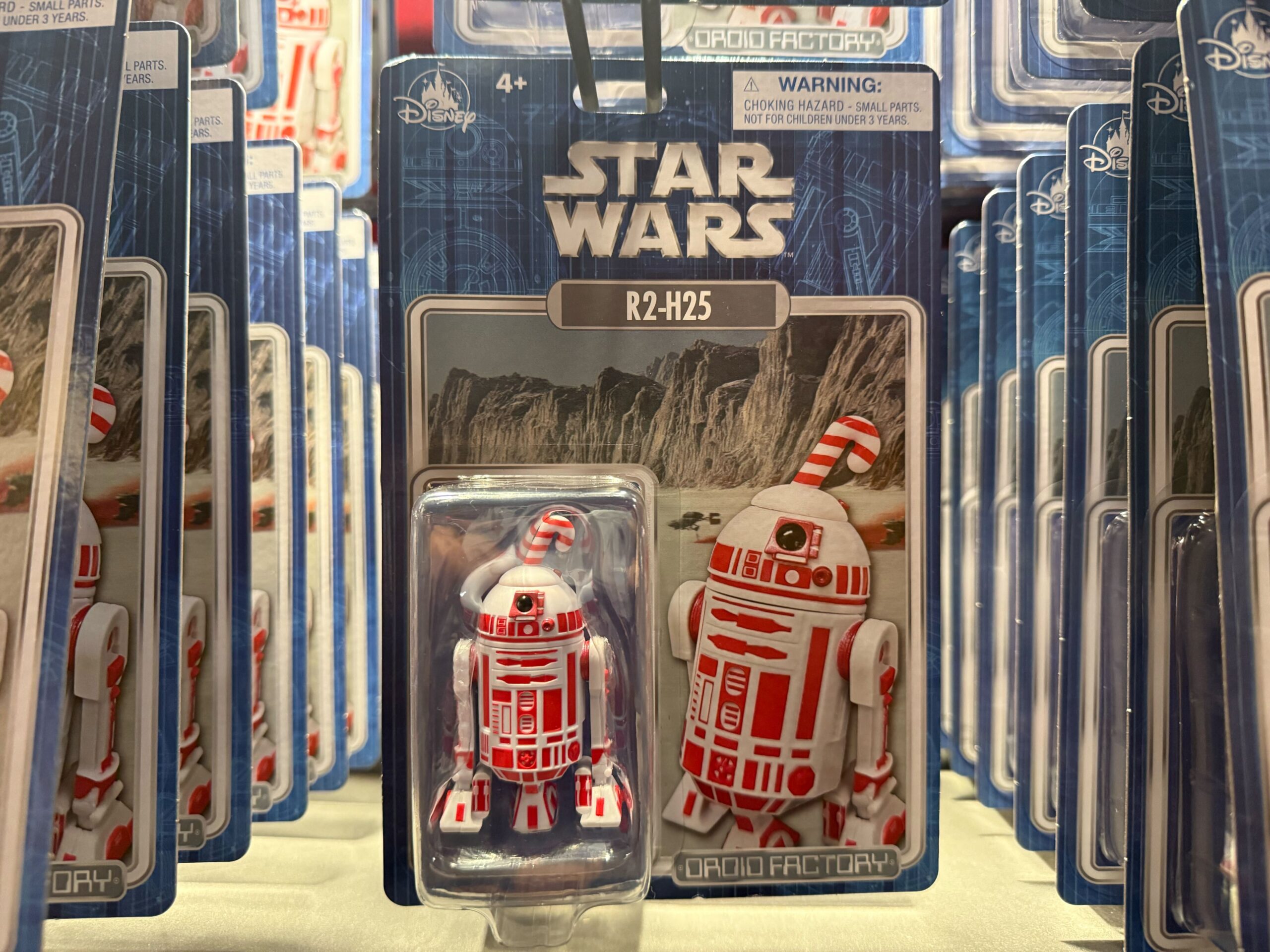 Rows of 2025 R2-H25 Star Wars droid action figures in Christmas packaging on display with Disneyland merchandise prices.